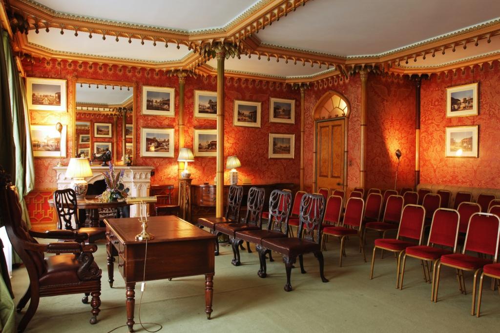 Red Drawing Room in Royal Pavilion with rich red wallpaper, ideal for meetings and events.