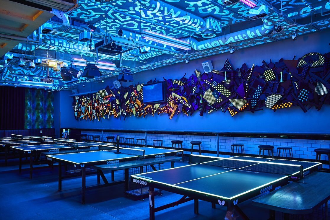 Vibrant event space with illuminated ping pong tables for team-building activities.