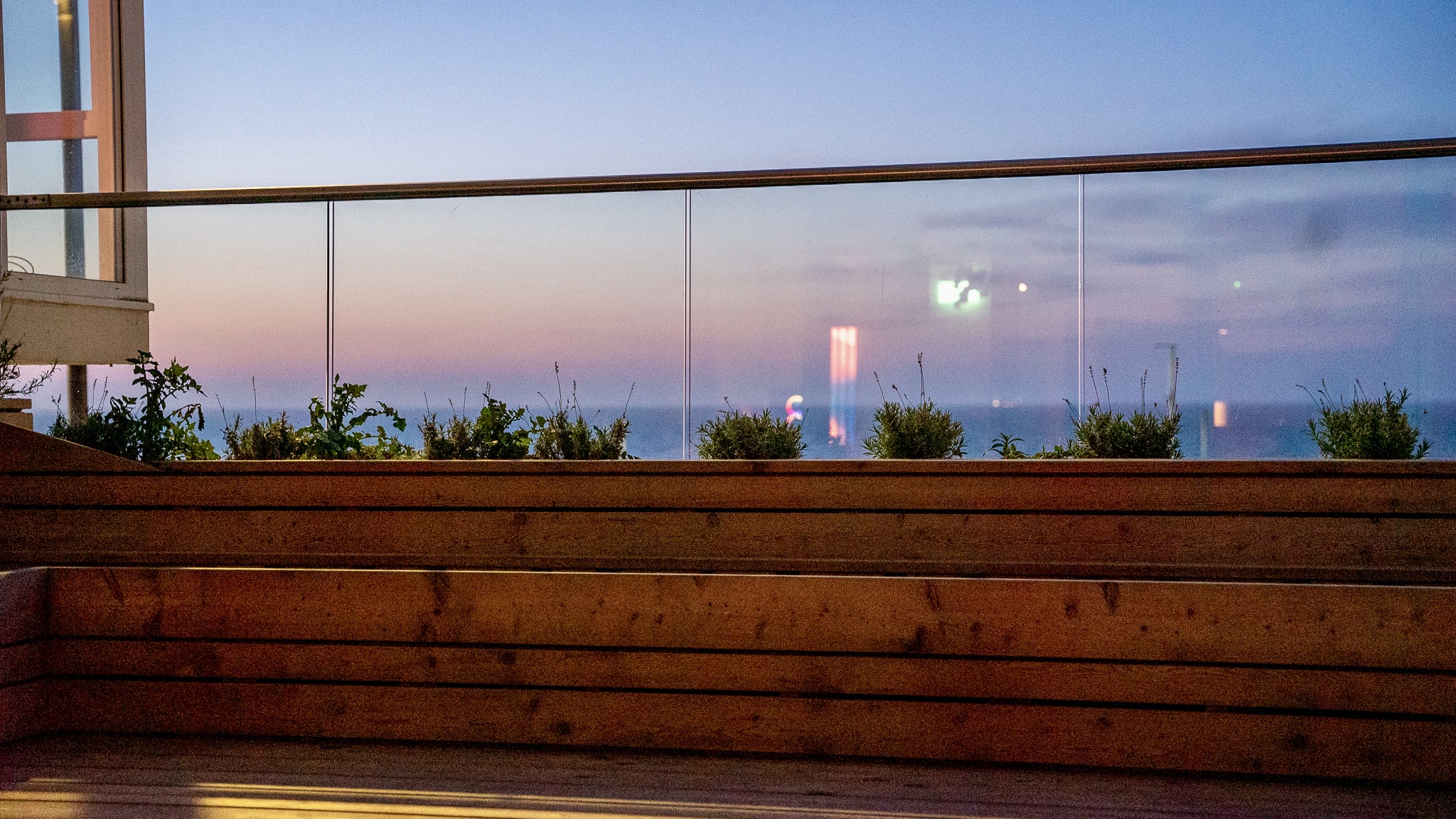 Outdoor venue with wooden seating and ocean view, ideal for cocktail receptions.
