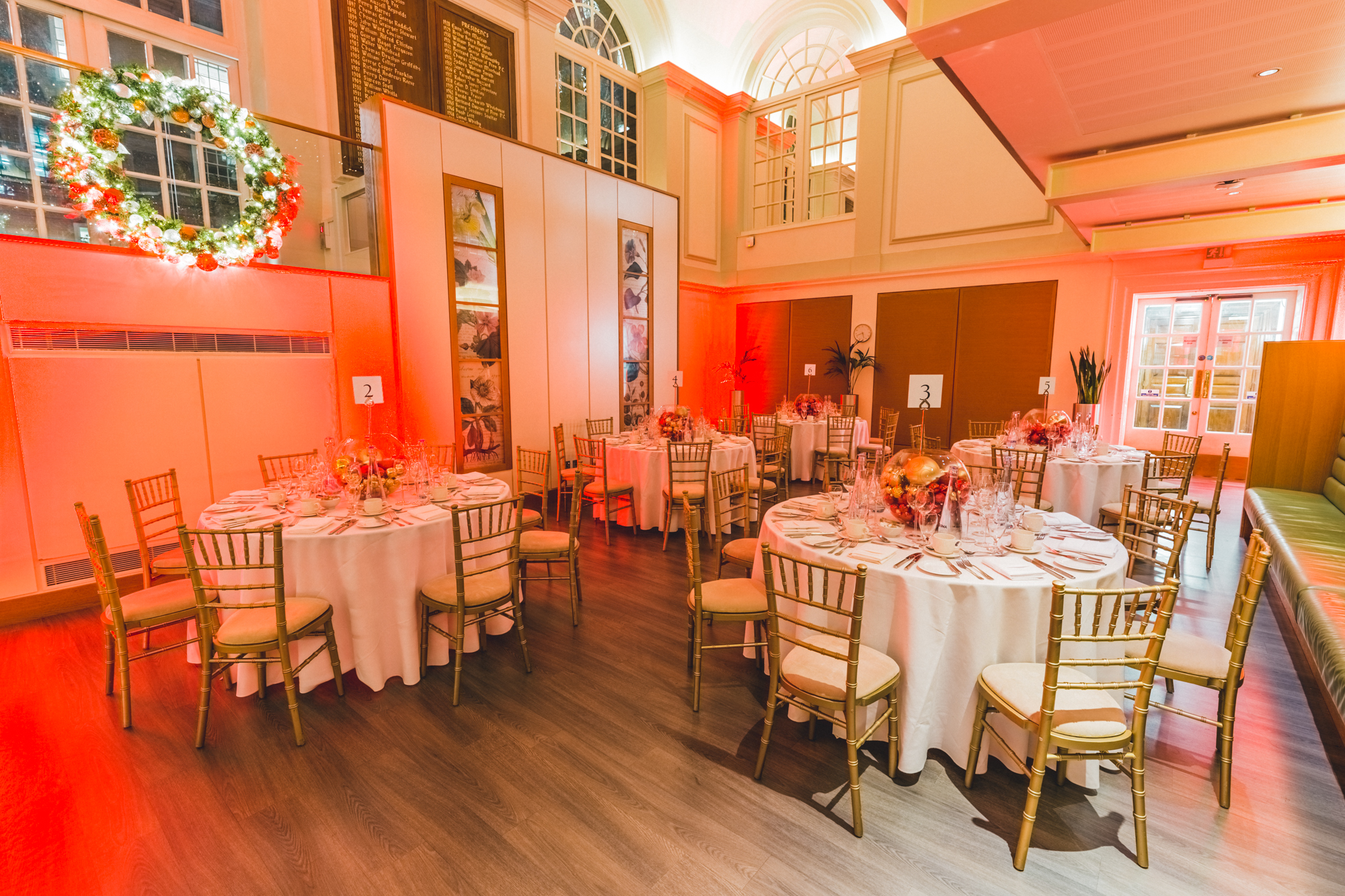 Elegant Christmas party setup with round tables and gold chairs at BMA House.