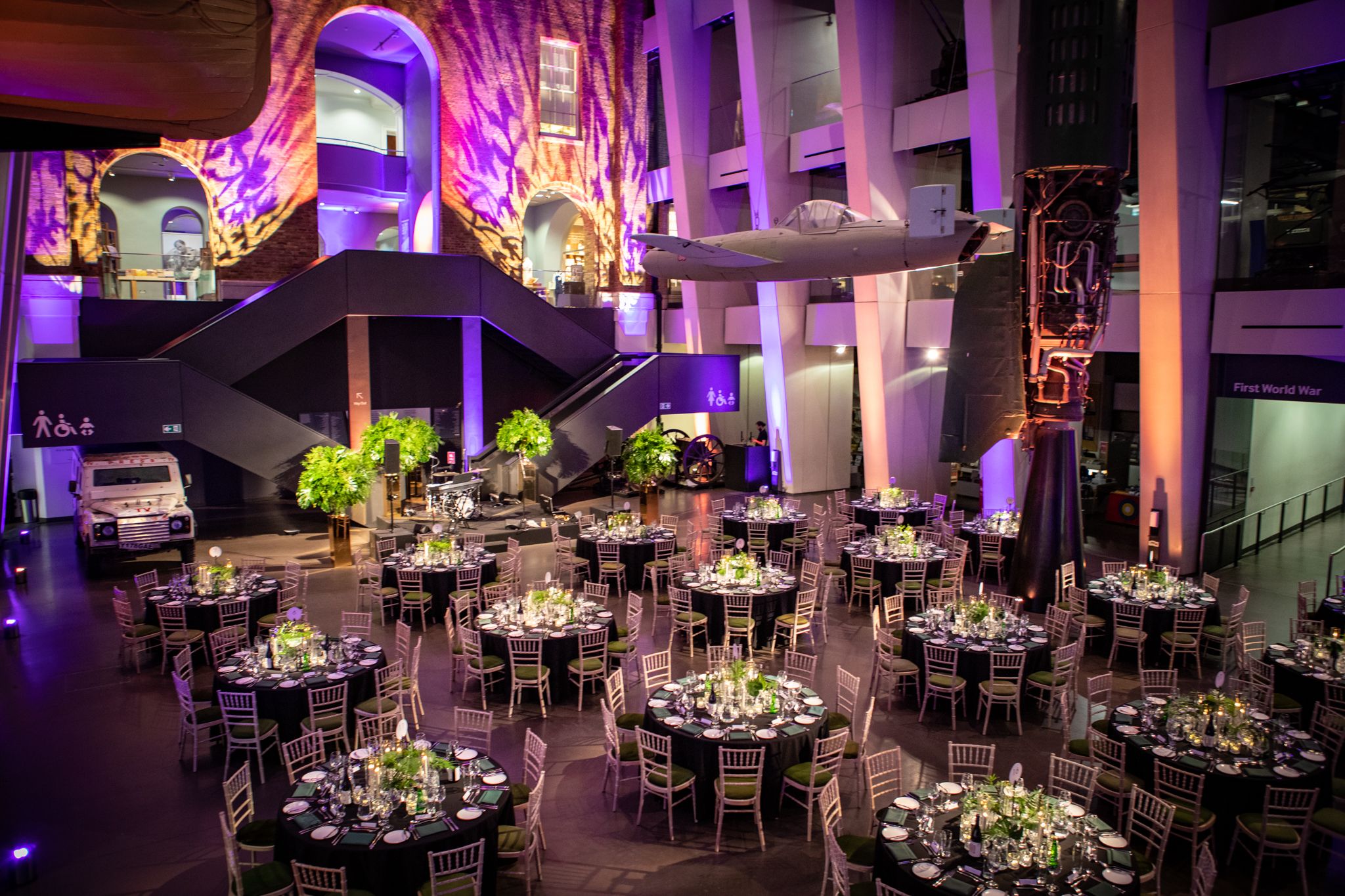Atrium at IWM London set for a gala with elegant tables and floral centerpieces.