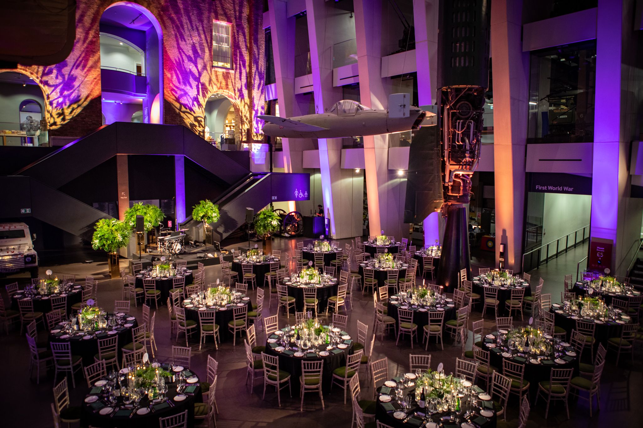 Atrium at IWM London, elegant gala setup with fine dining and warm ambiance.