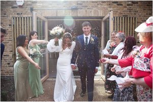 Joyful couple exits wedding venue under confetti at The Glass House Sky Room.
