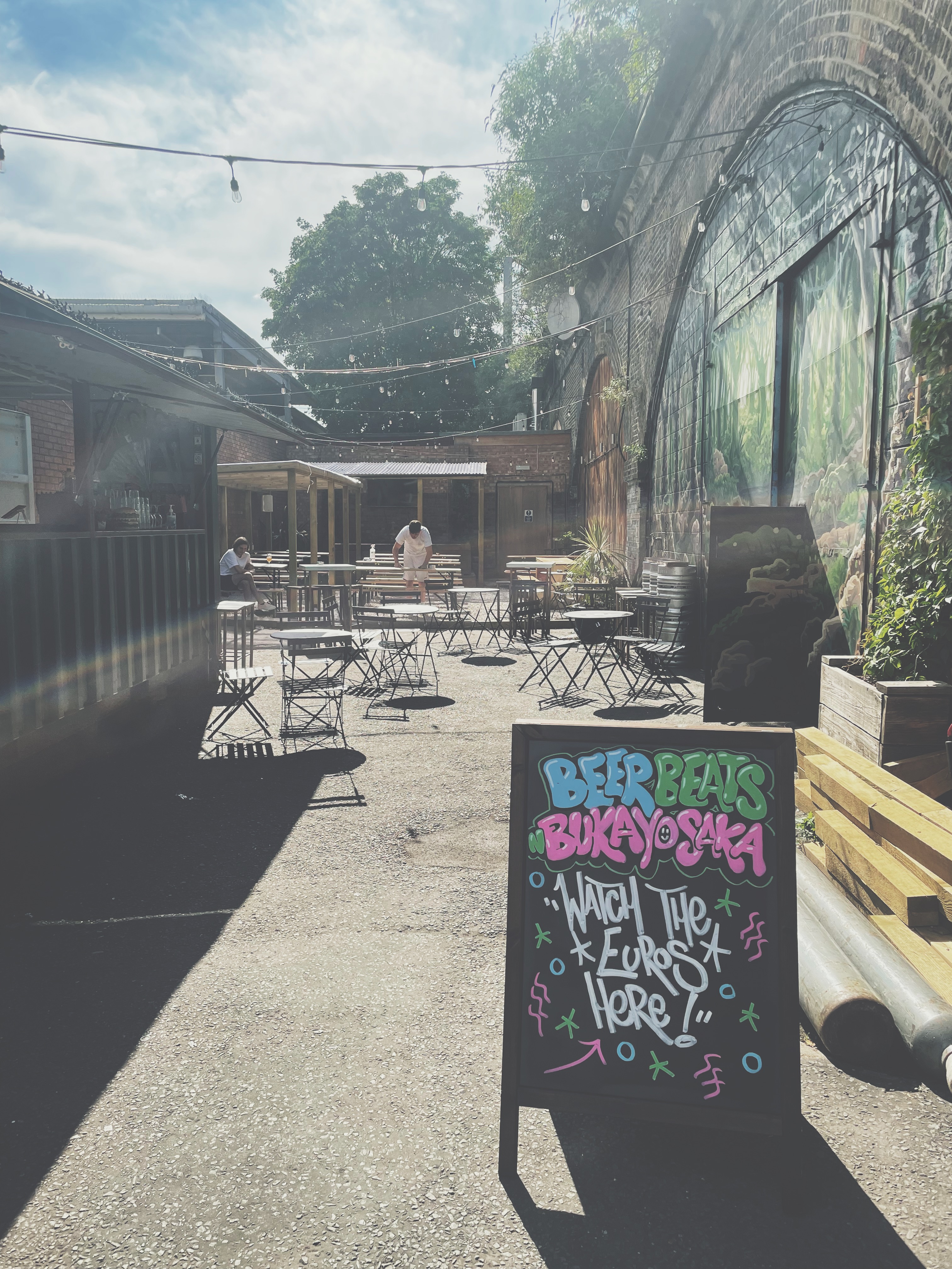 Outdoor event space at Deviant & Dandy Brewery with vibrant signage for craft beverages.
