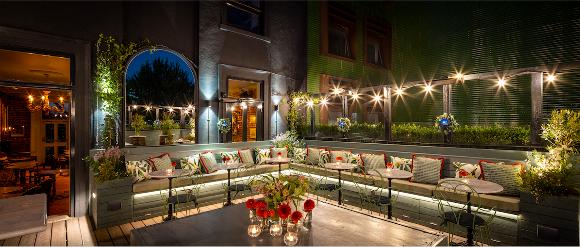 Outdoor event space at The Lock Tavern with ambient lighting and lush greenery.