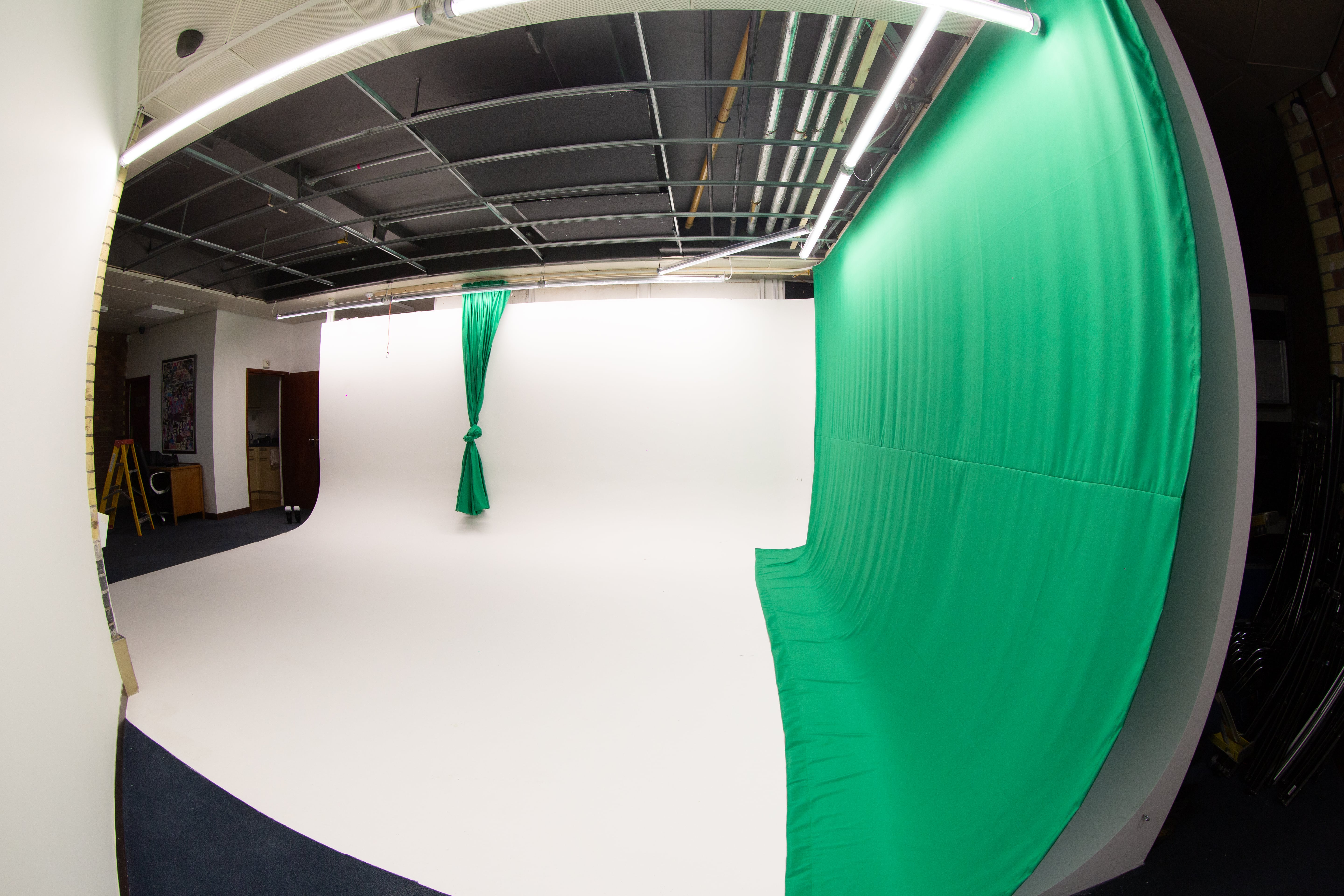 Infinity Cove Film studio with white backdrop and green screen for video production events.