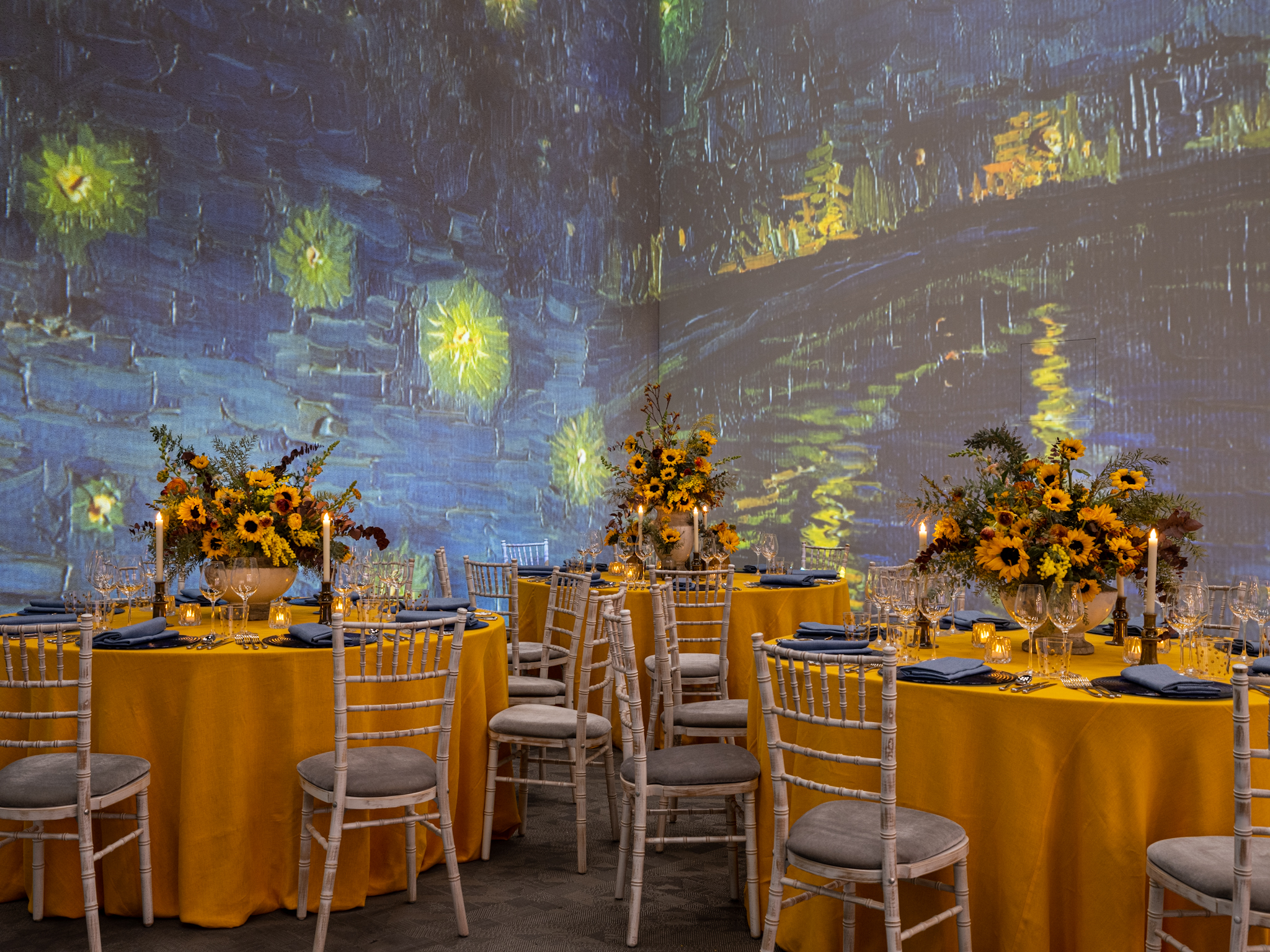 Elegant event space with yellow table linens and starry night projection for upscale gatherings.
