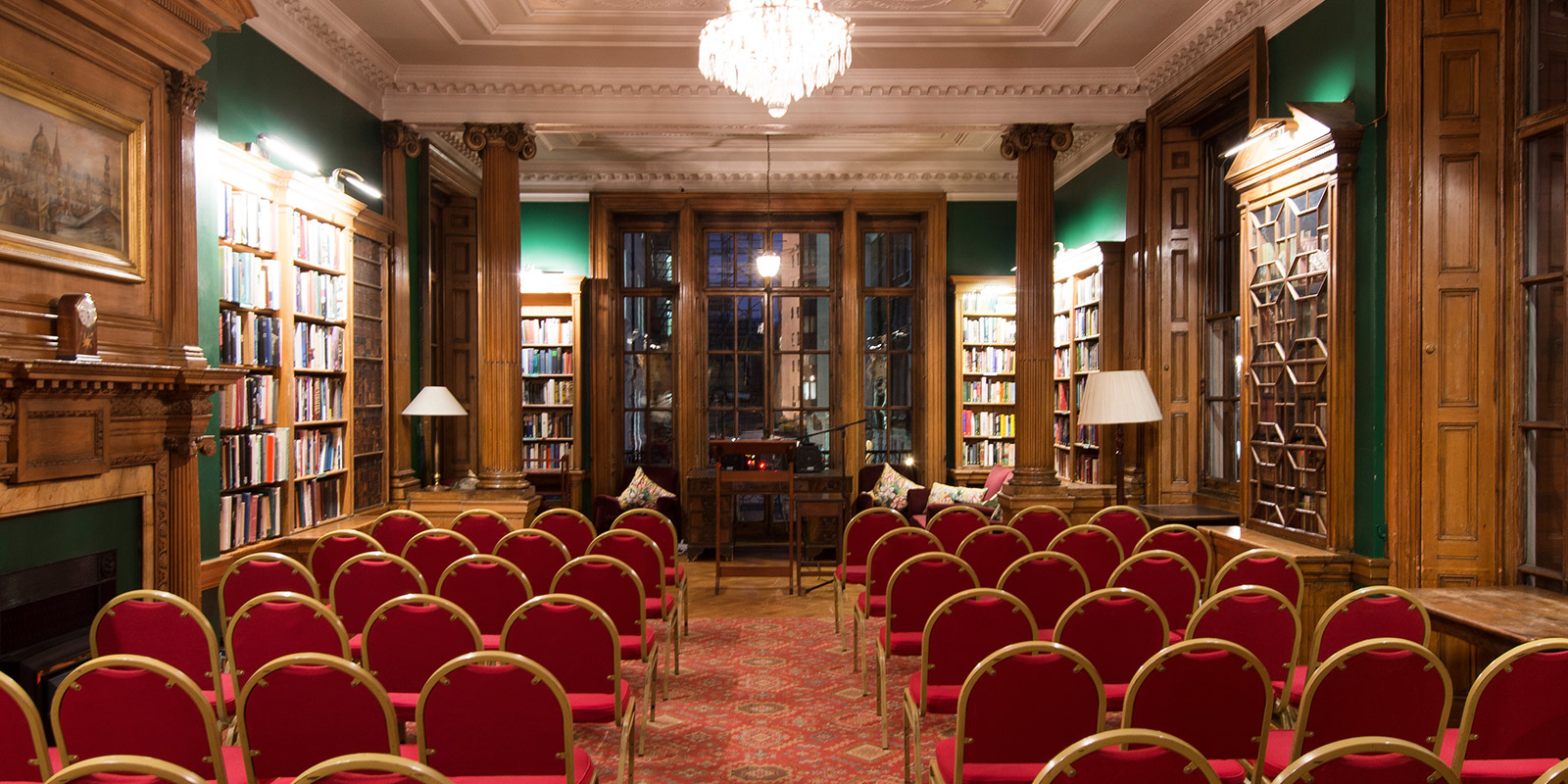 Elegant library meeting space with red chairs for intimate gatherings and presentations.