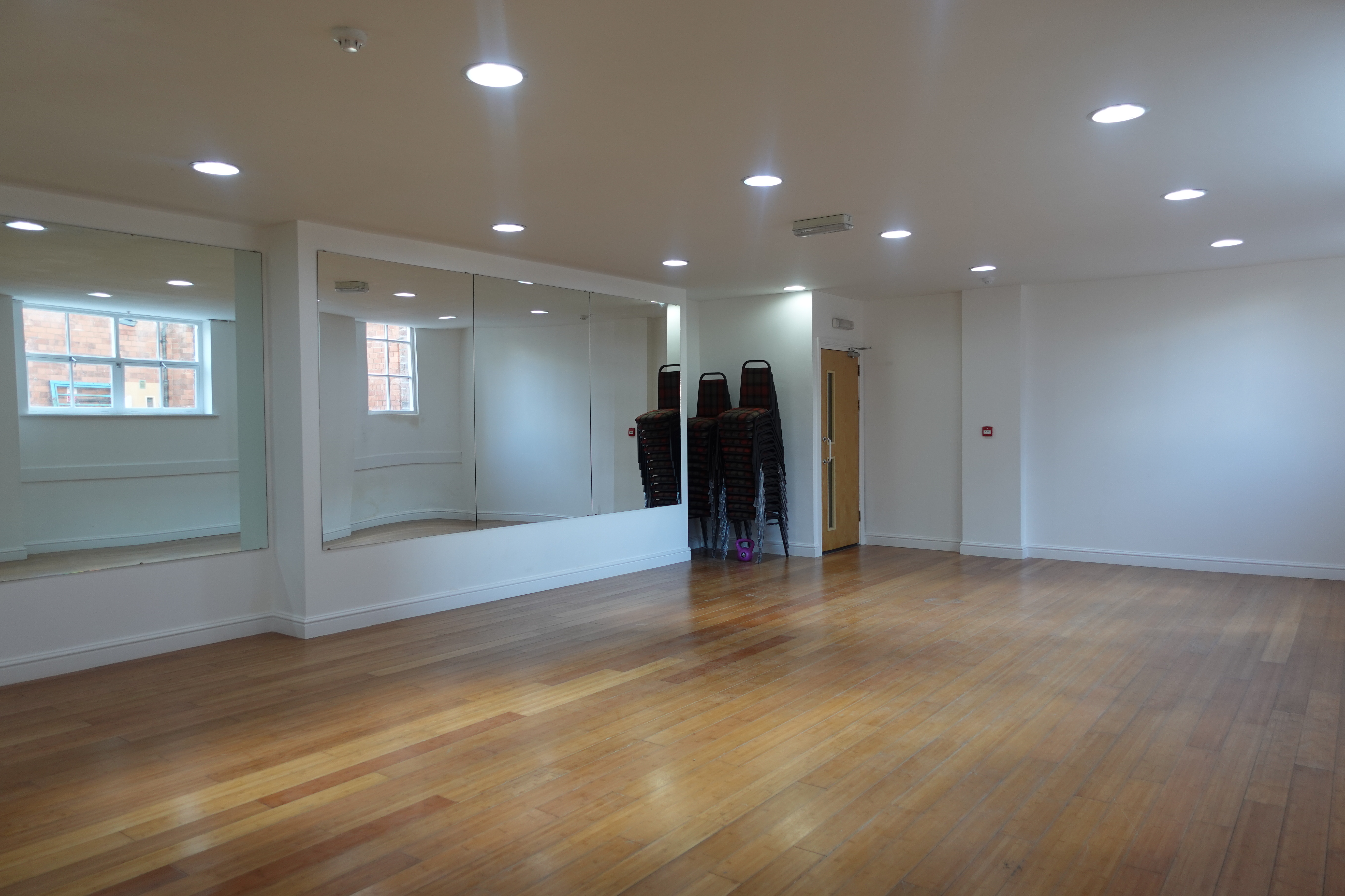 Versatile meeting space with polished wooden floors, ideal for workshops and fitness classes.