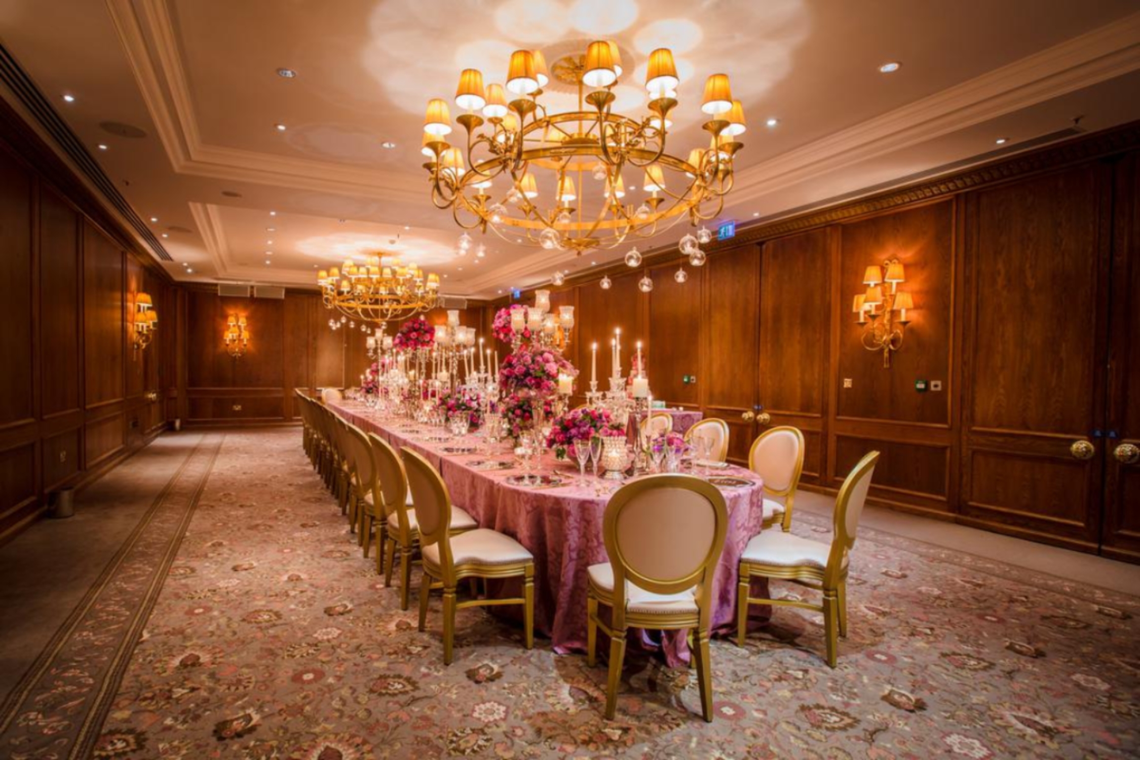 Elegant banquet room at Four Seasons London, featuring pink tablecloth and floral centerpieces.