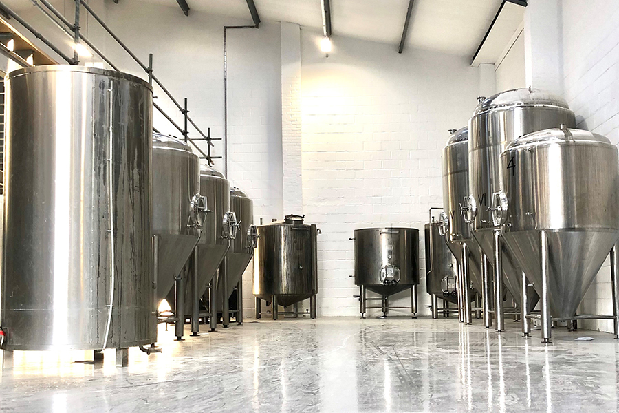 Modern brewery venue with stainless steel tanks for corporate events and team-building.