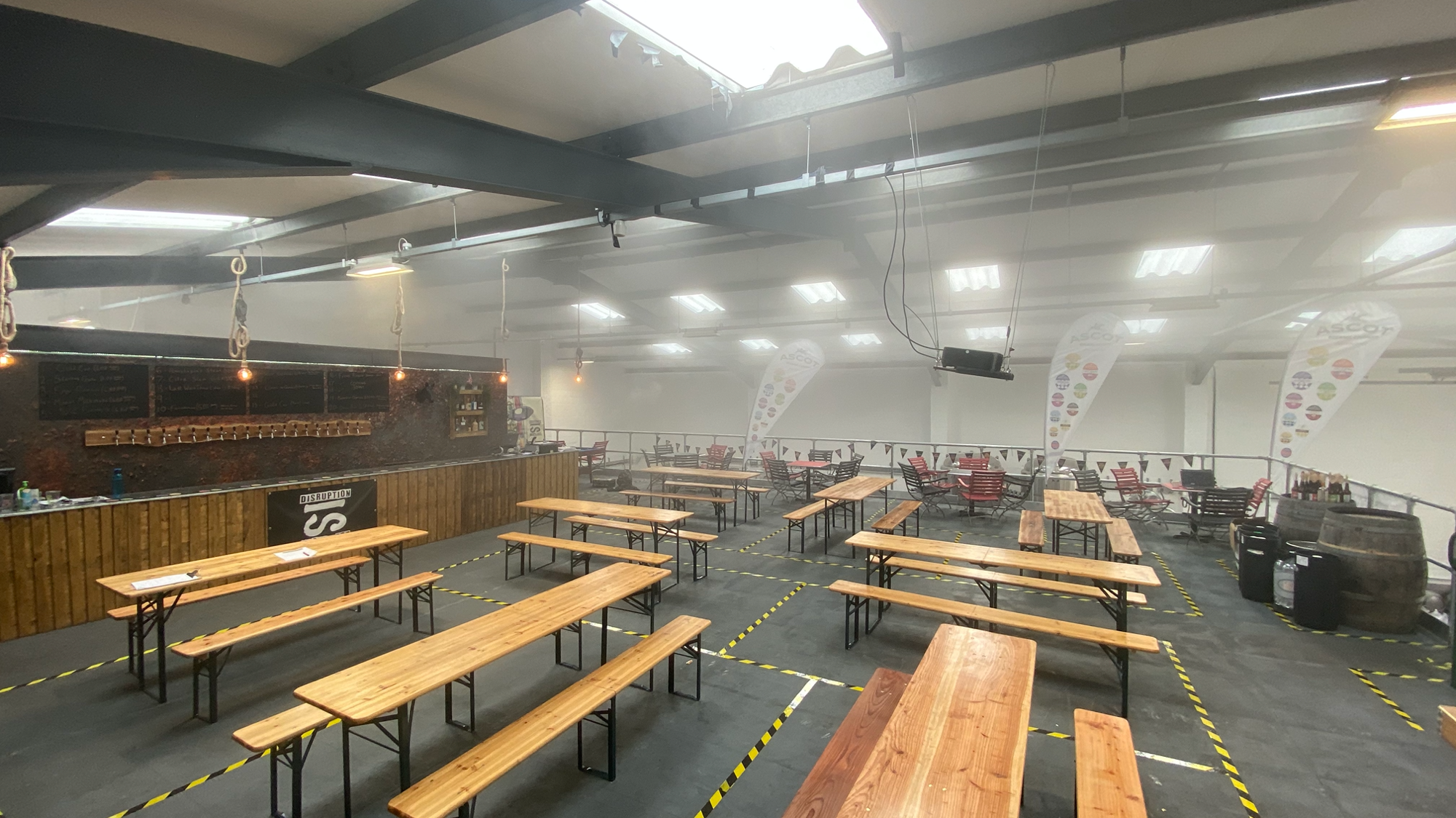 Spacious event venue with wooden tables in The Mezzanine, ideal for networking and dining.