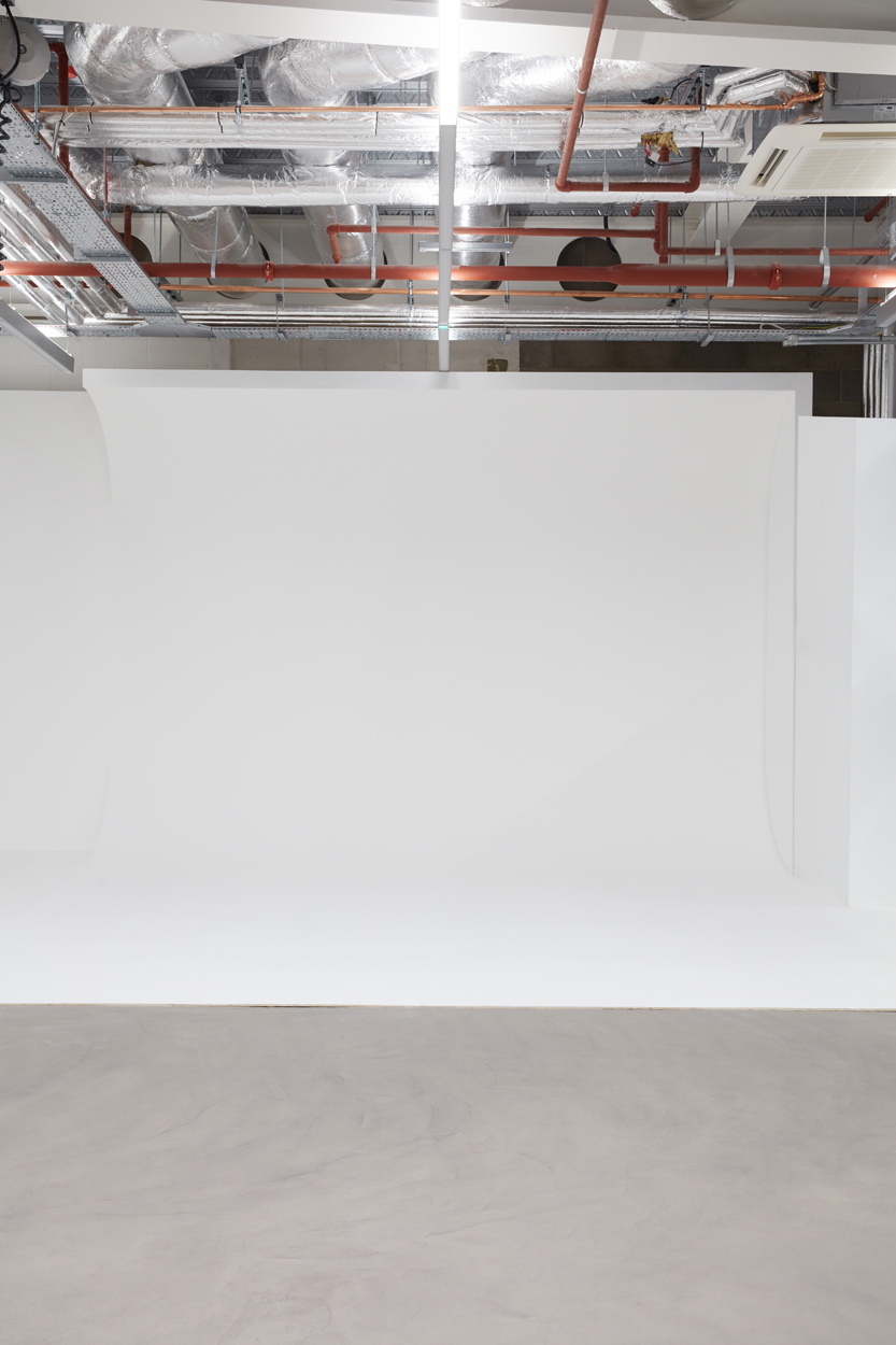 Minimalist event space with white backdrop, ideal for presentations and product launches.