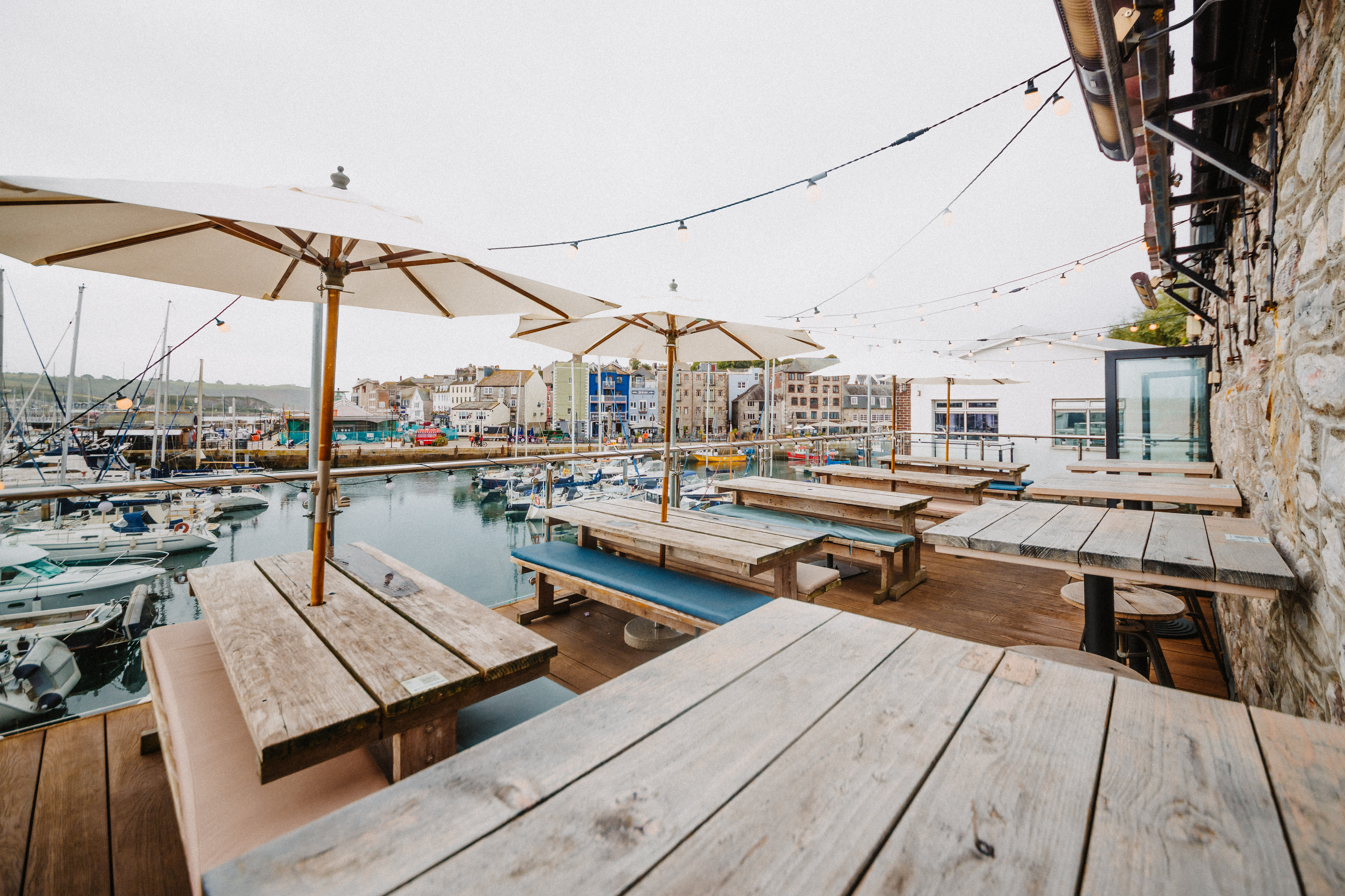 Charming waterfront venue with rustic tables, perfect for outdoor events and gatherings.