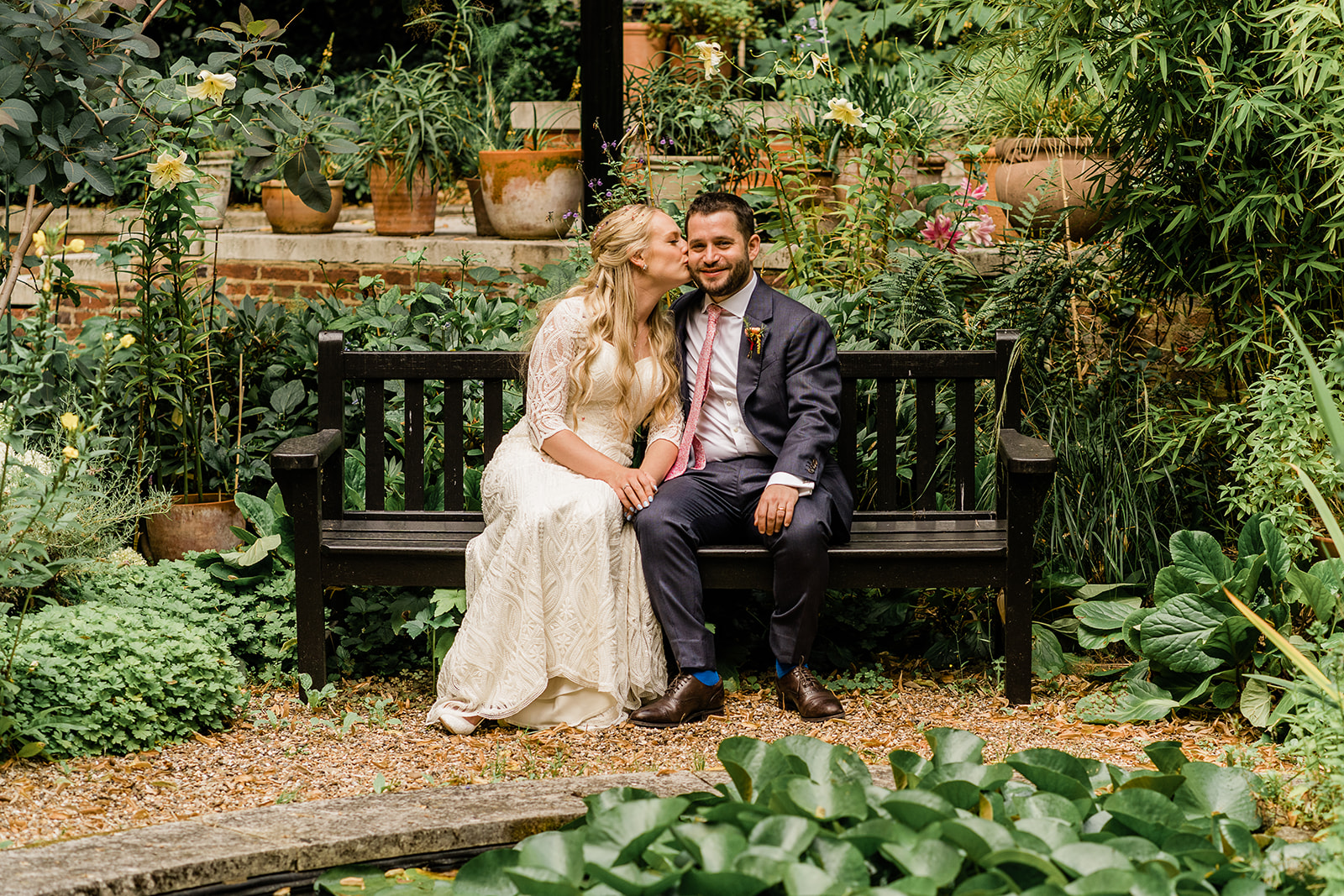 Intimate couple in lush garden at BMA House for outdoor wedding event.