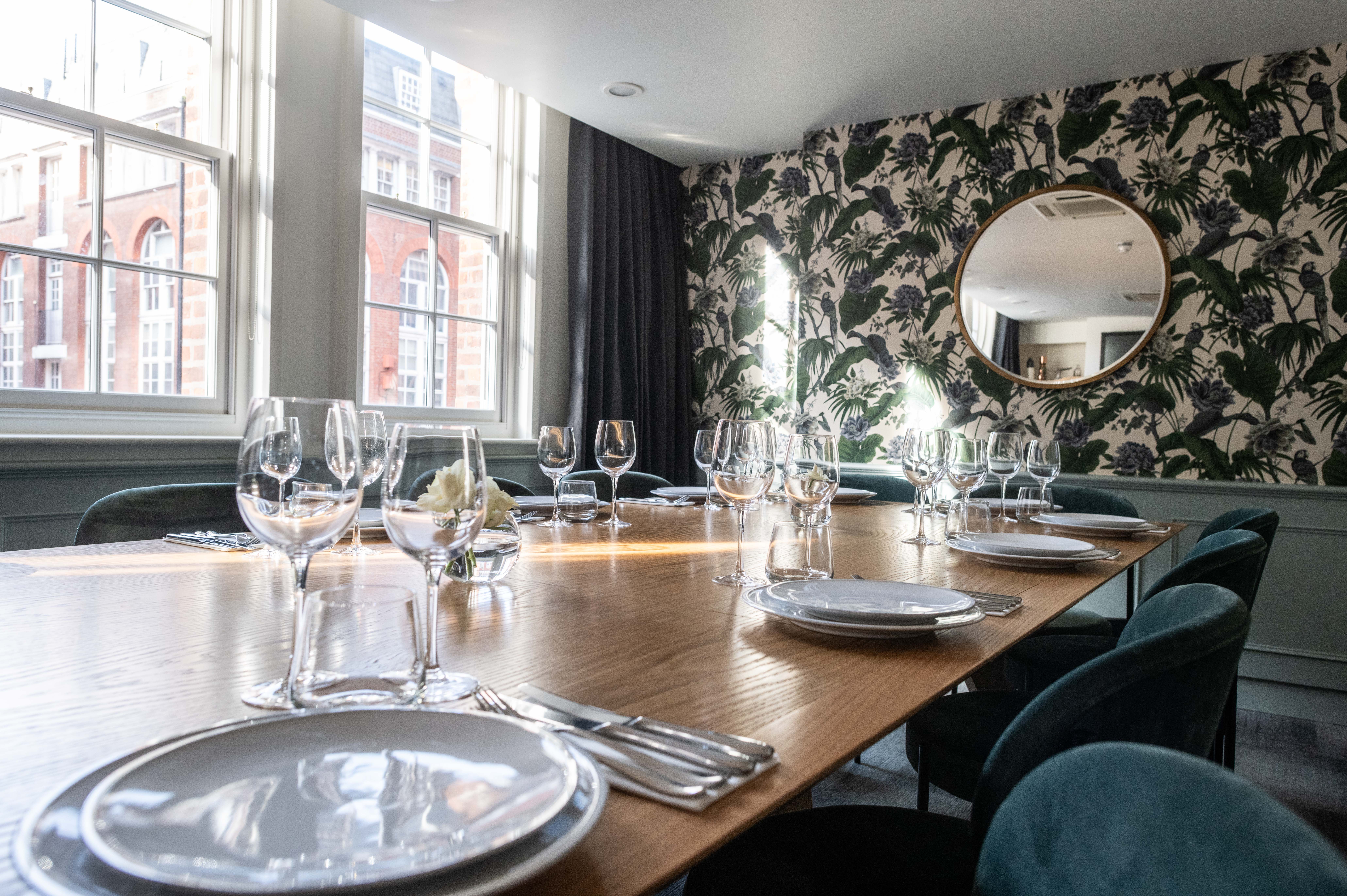 Elegant dining table with polished glassware in a tropical-themed meeting space.