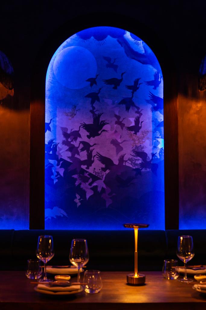 Sican event backdrop with bird silhouettes in vibrant purple and blue hues.