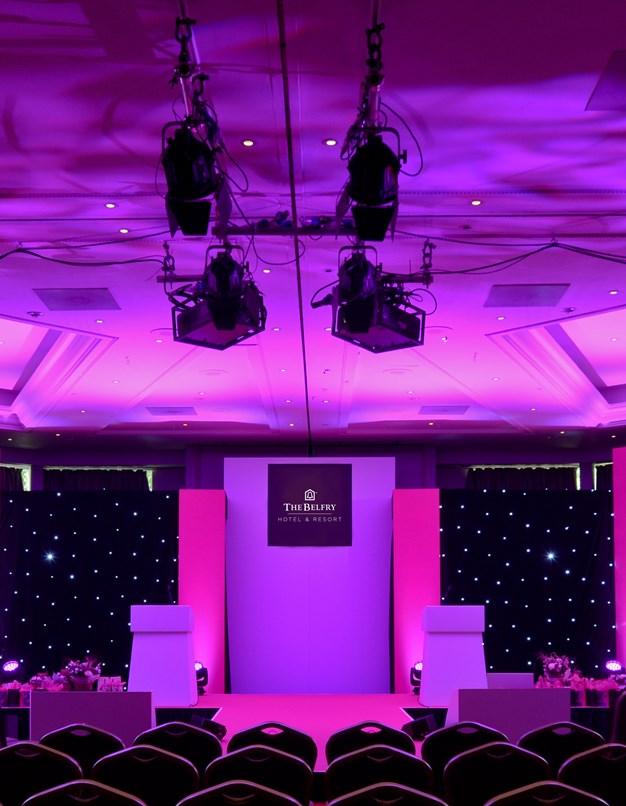Woodland Suite at The Belfry: elegant event space with stage and purple lighting.
