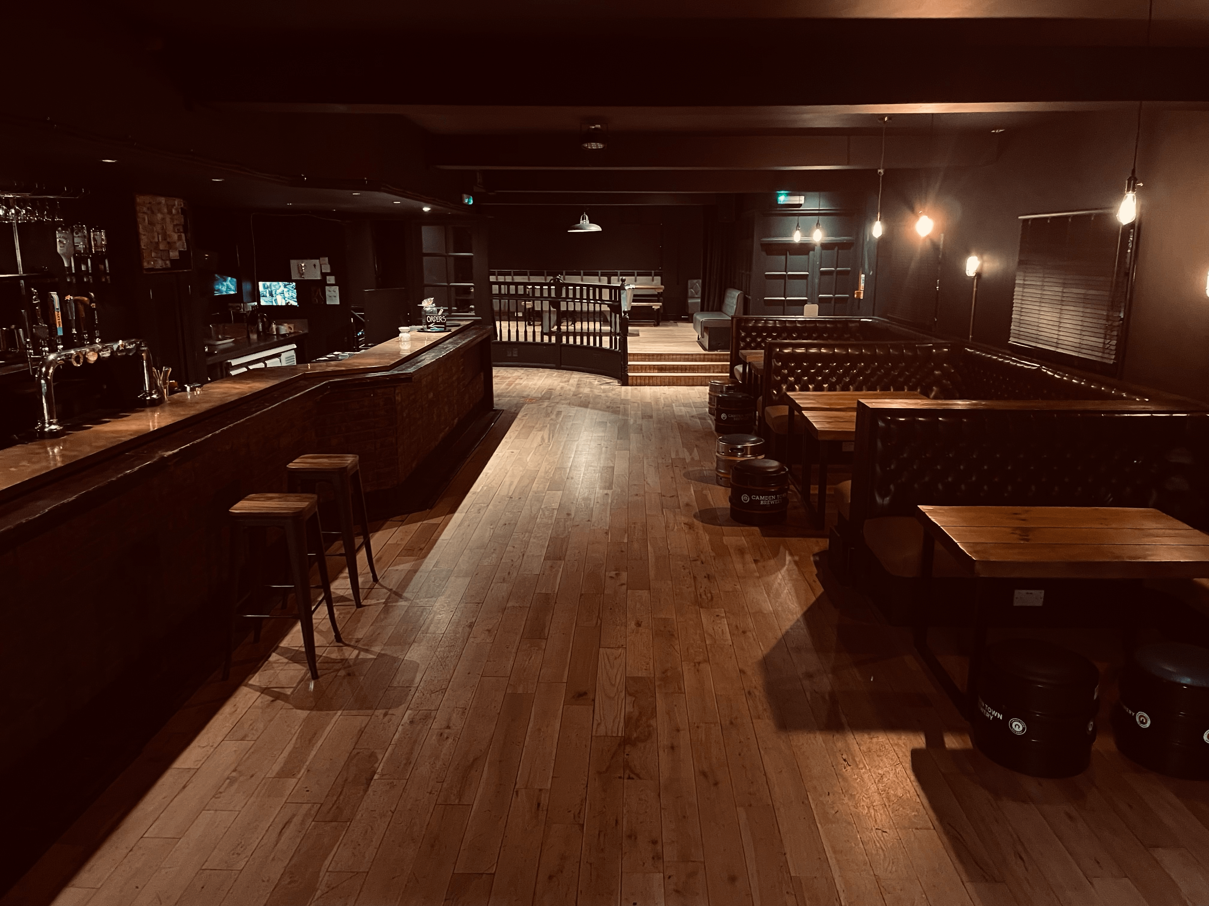 Spacious dimly lit venue with polished wood floor, ideal for networking events and gatherings.