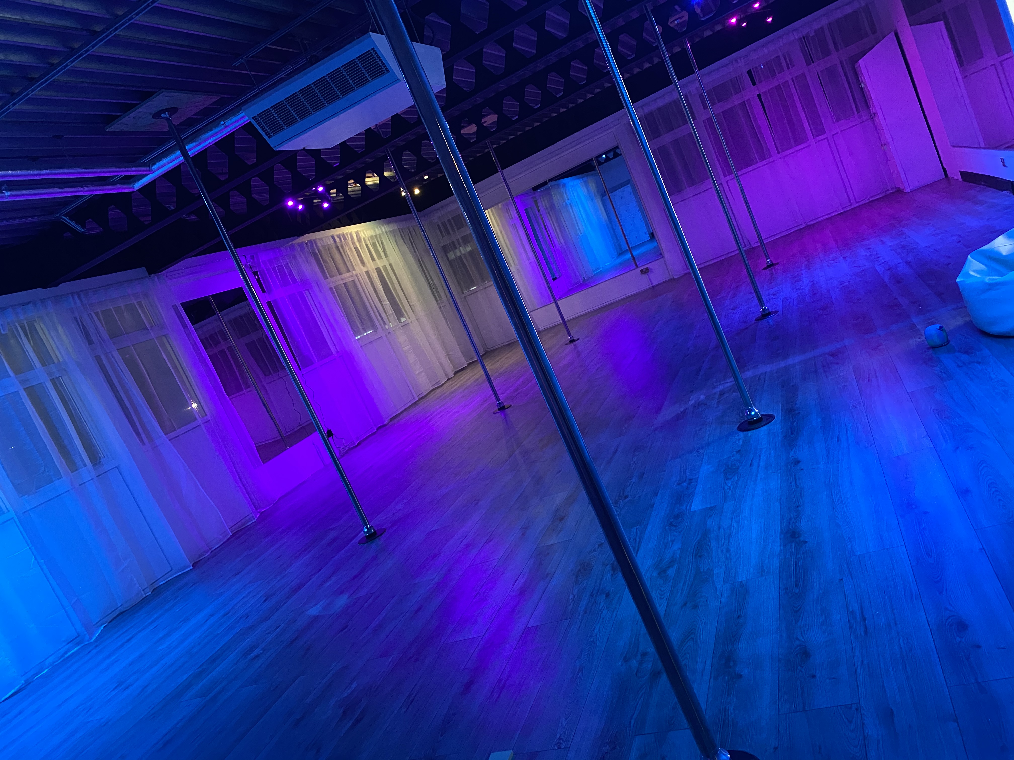 Versatile event space with polished floors and elegant drapery for dance classes and parties.