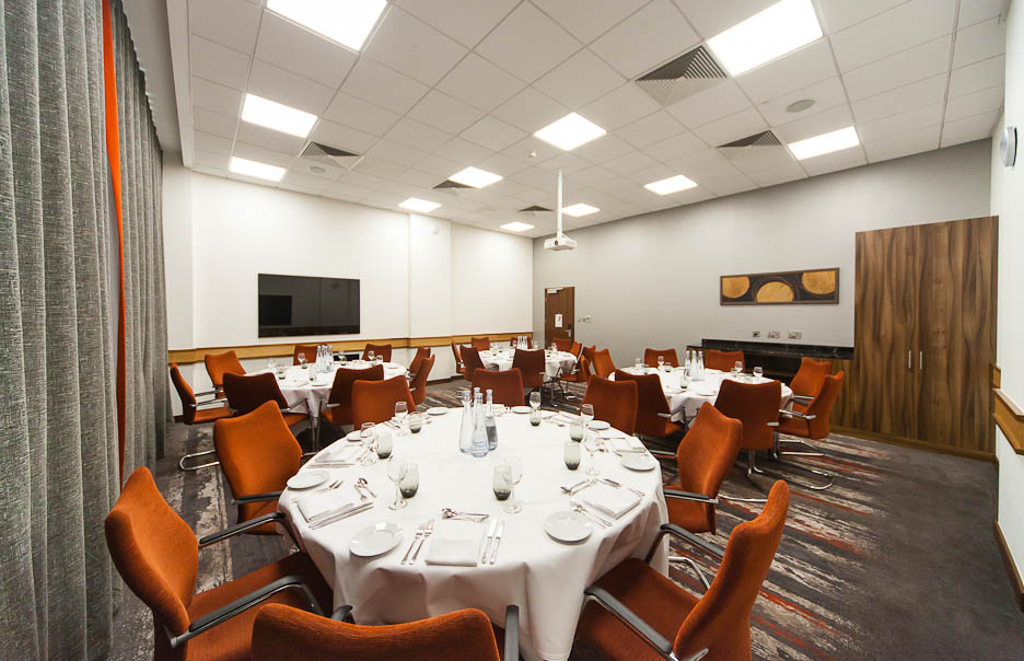 Meeting room 7 at Clayton Hotel Leeds, elegant dining setup with round tables and orange chairs.