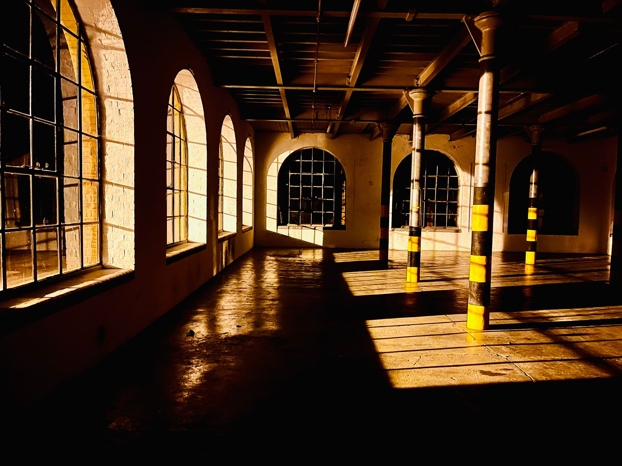 Spacious industrial venue with arched windows, perfect for creative events and workshops.