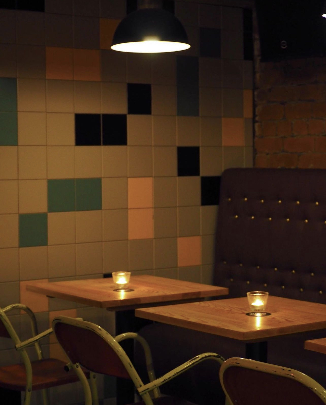 Cozy meeting space with wooden tables and colorful tiled wall for intimate gatherings.