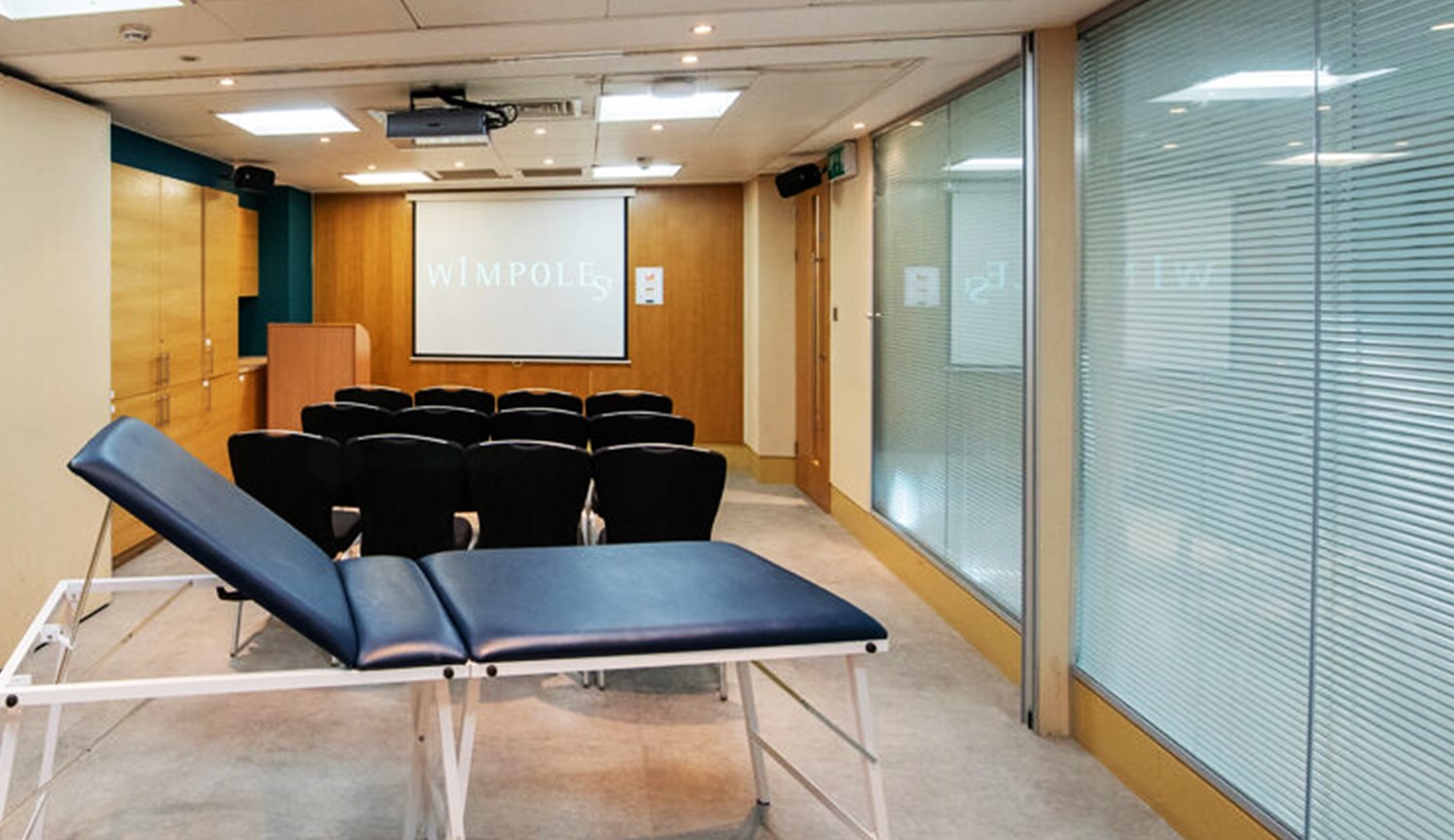 Versatile training suite with seating and treatment table for wellness events and seminars.