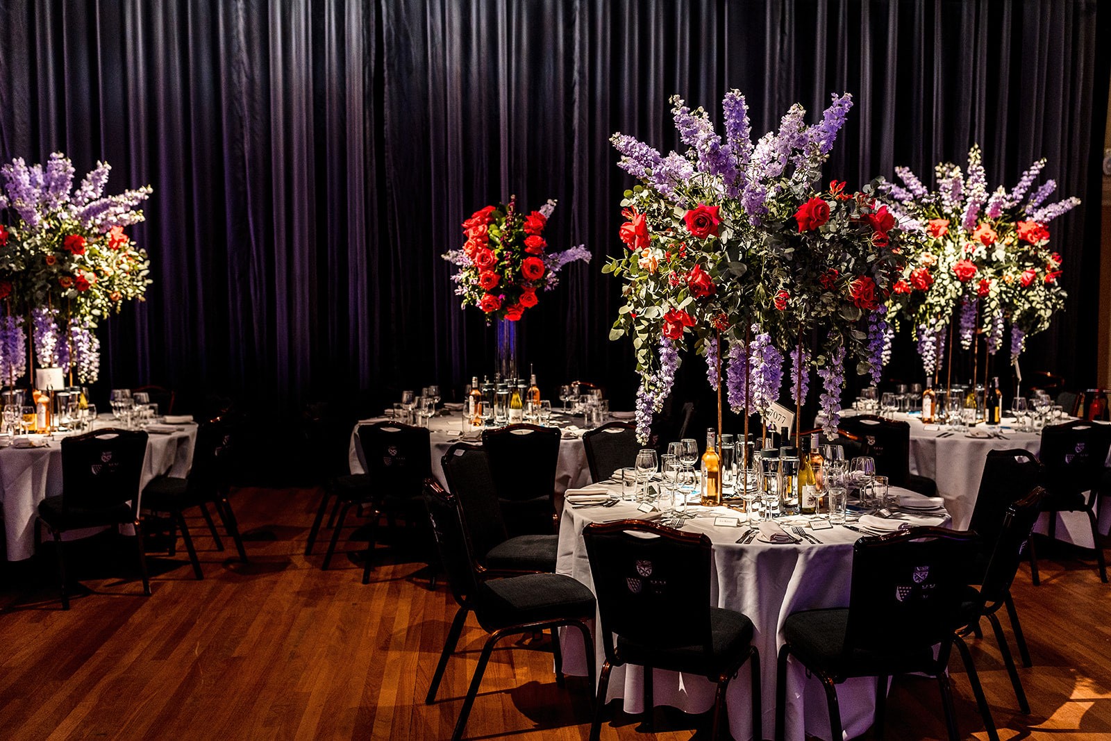 Elegant wedding banquet at Glaziers Hall with floral centerpieces and dark drapery.