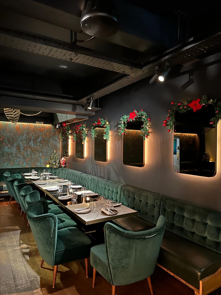 Stylish restaurant with green seating, ideal for holiday parties and corporate events.