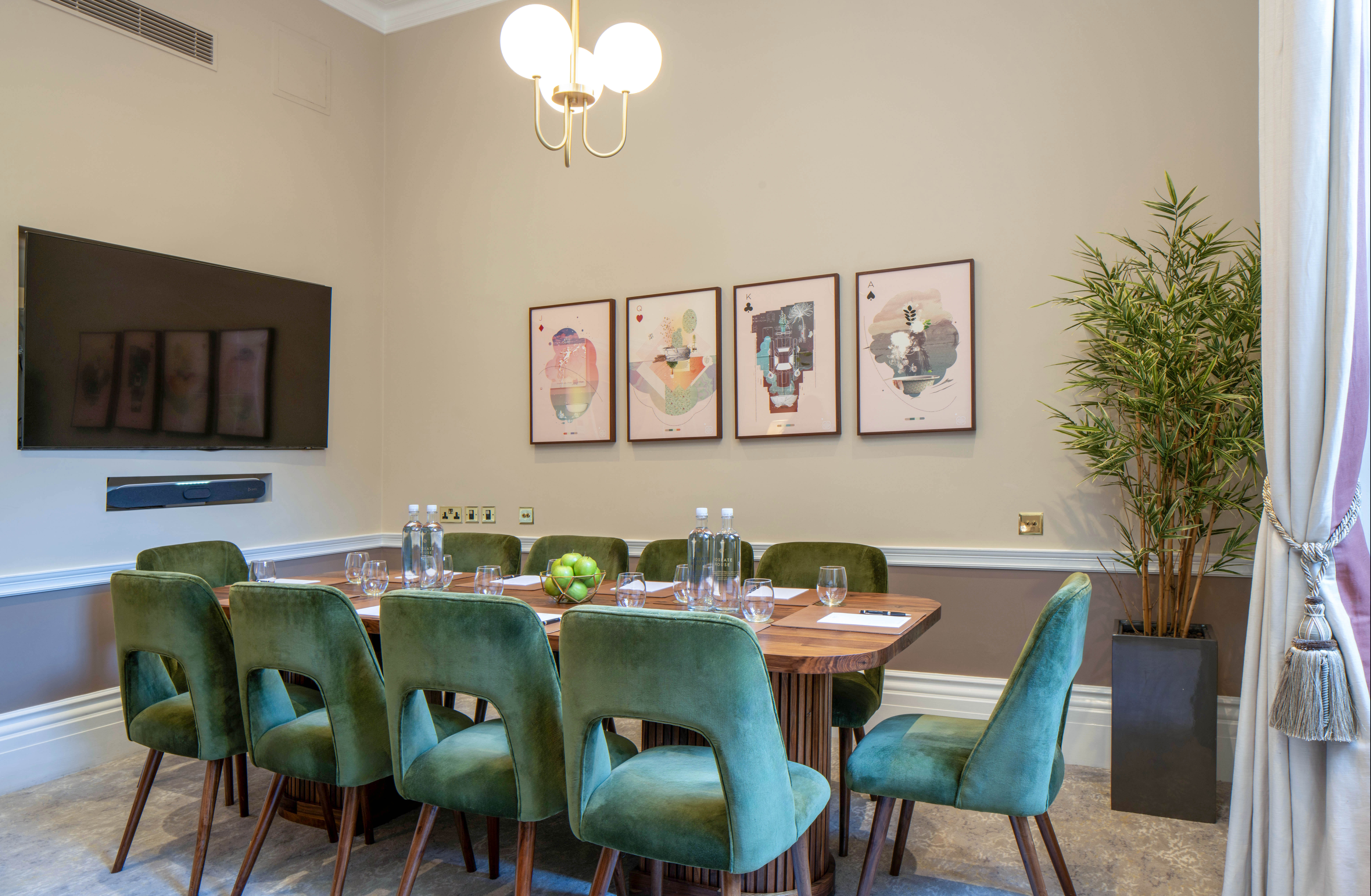 Intimate meeting room at Club Priv'e with stylish green chairs and modern tech.