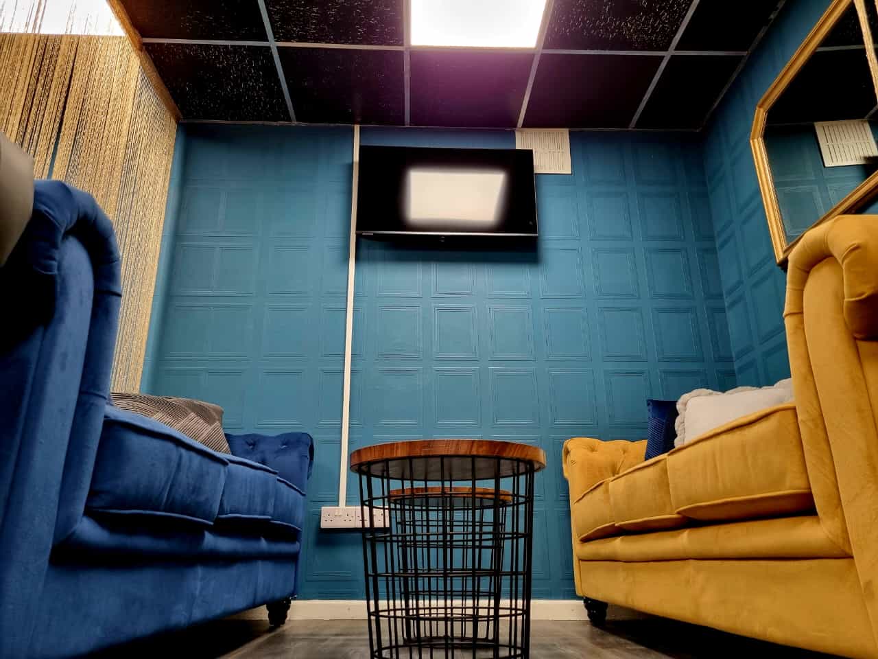 Cozy Al-Miski Lounge with blue walls, yellow couch for meetings and brainstorming sessions.