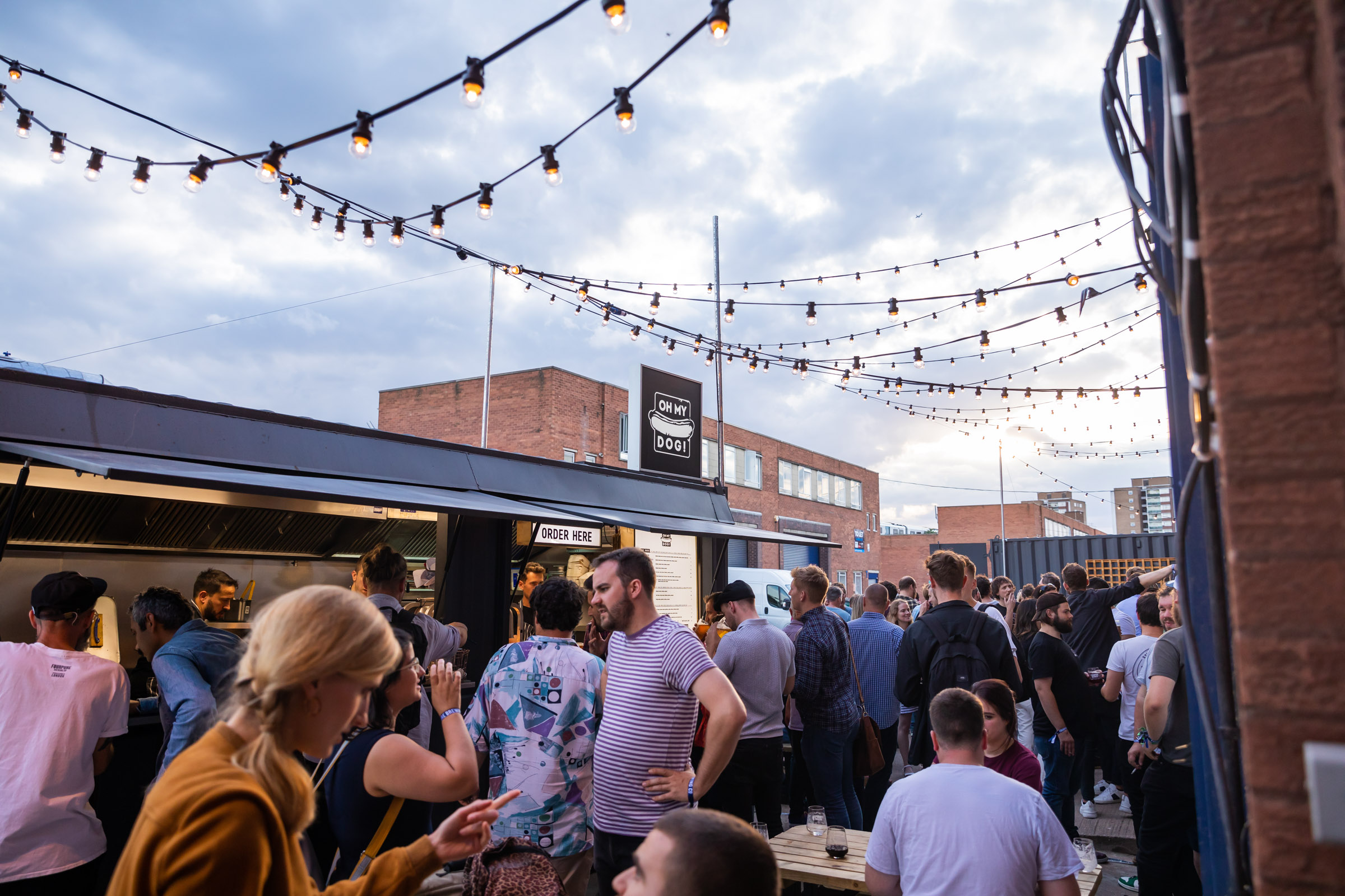 Vibrant outdoor event at Fourpure Taproom with string lights and food trucks.