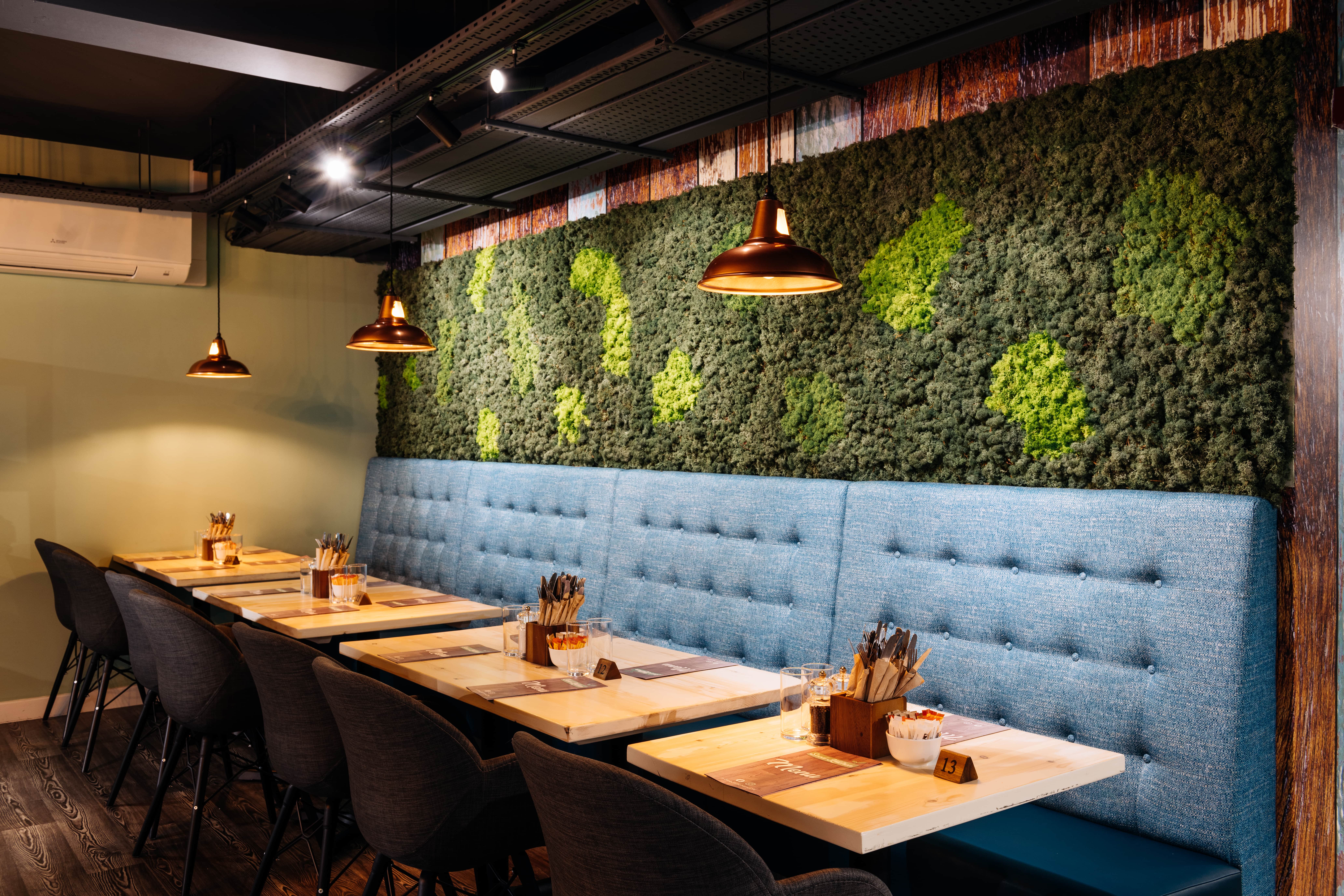 Modern dining space in Leslie Forster Suite, featuring plush blue seating and moss wall.