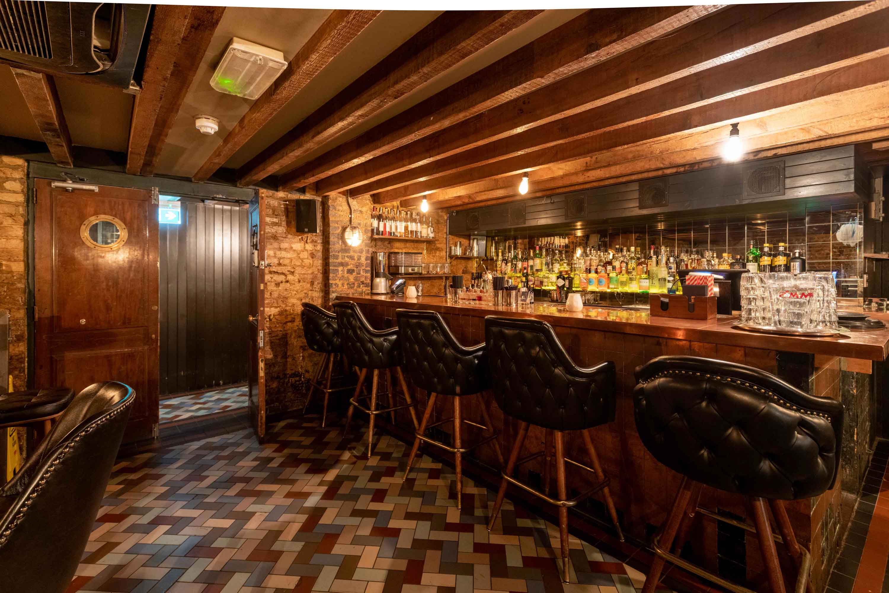 Stylish bar with exposed brick and wooden beams, perfect for gatherings and events.