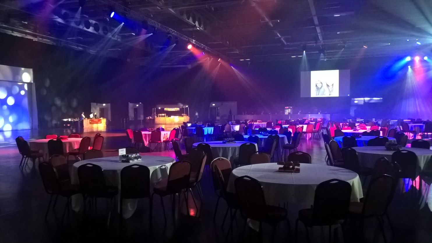 Elegant event space with round tables and colorful lighting for conferences or galas.