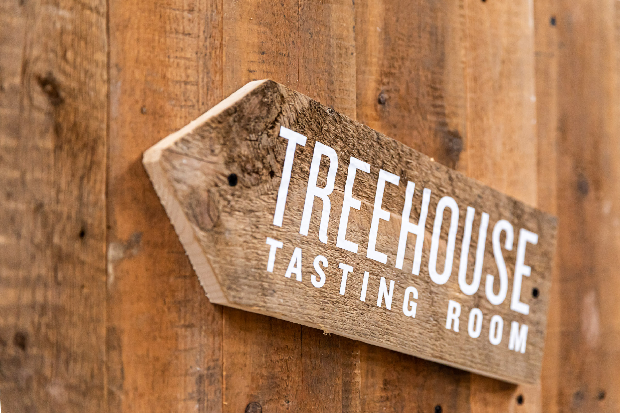 Rustic wooden sign at Treehouse Tasting Room, ideal for cozy events and tastings.