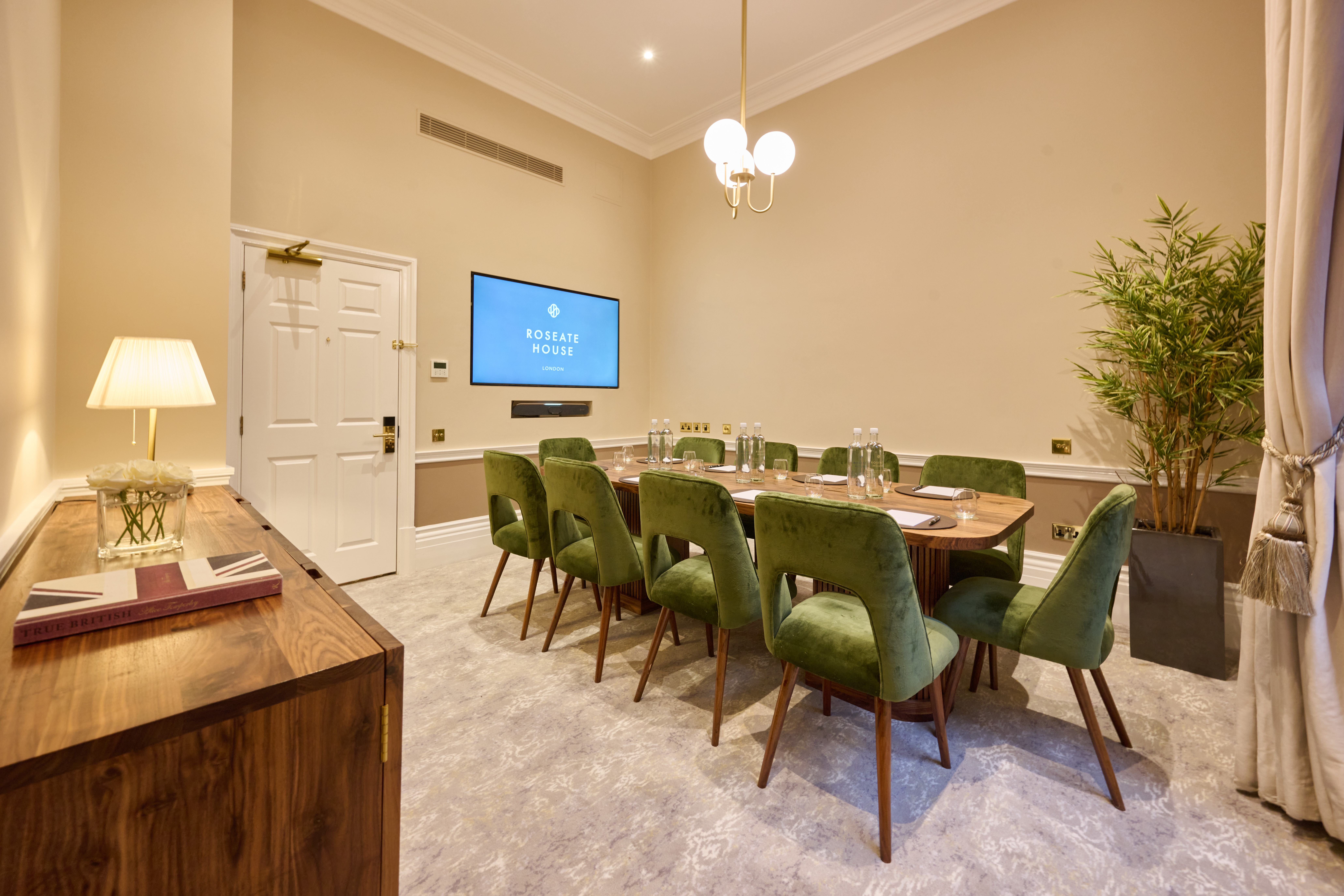 Club Privé meeting room in Roseate House London, featuring a large table and green chairs.