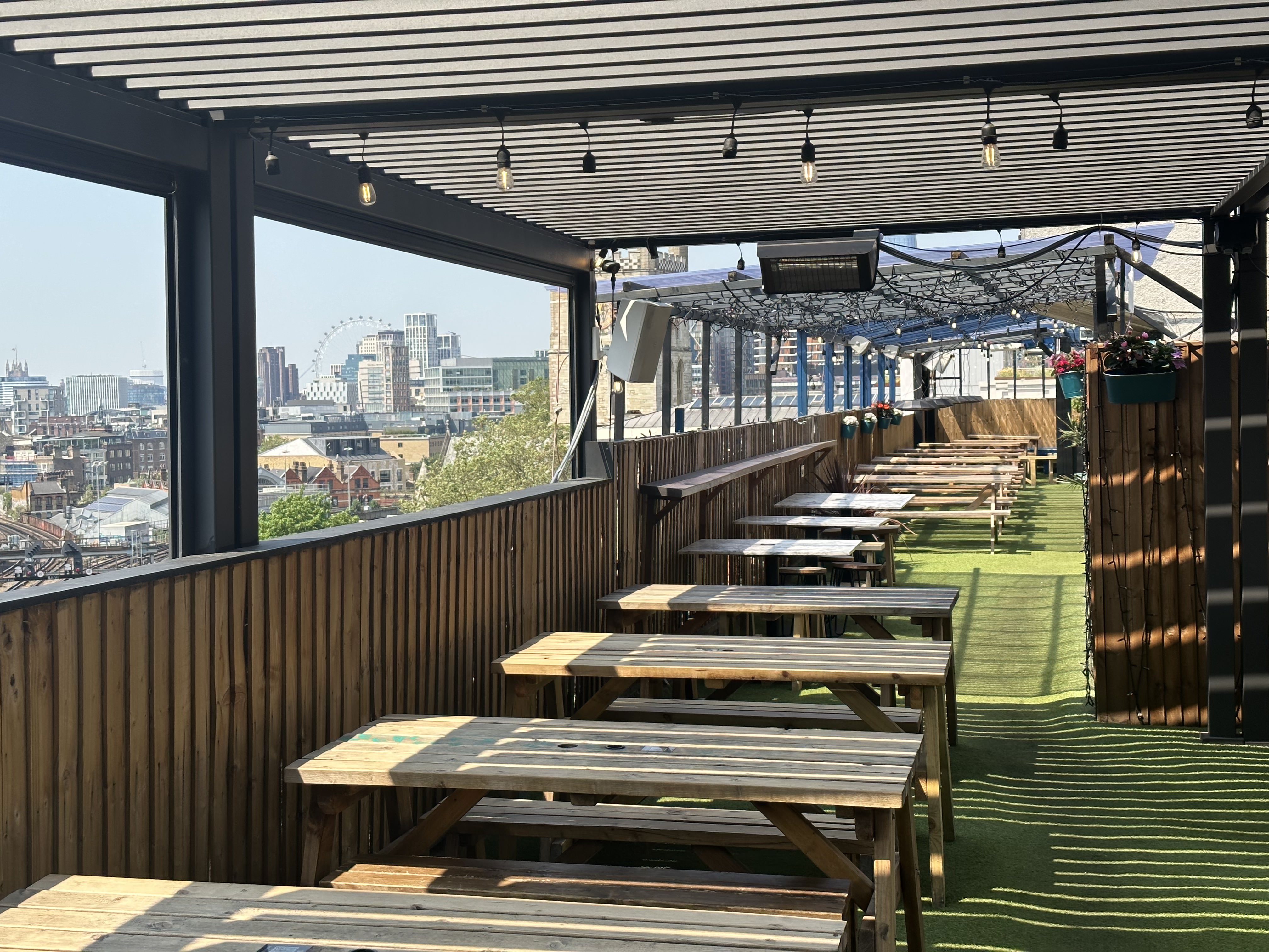 London Bridge Rooftop venue with wooden tables and city skyline, ideal for summer events.