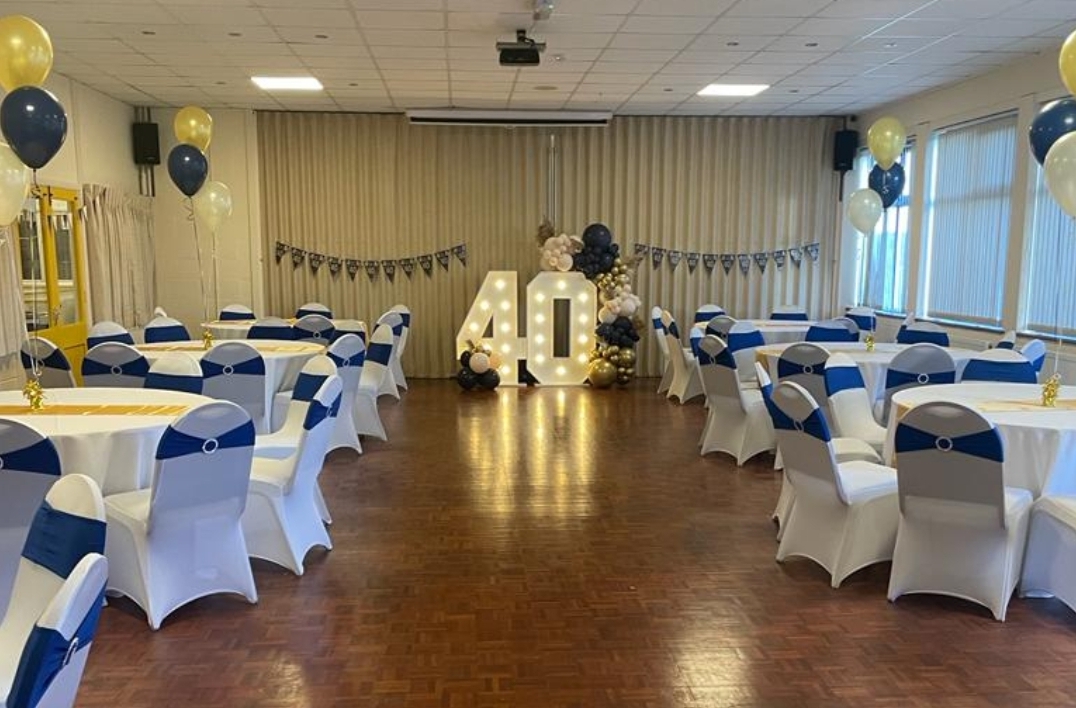 Elegant event space for 40th birthday with blue sashes and illuminated "40" signage.