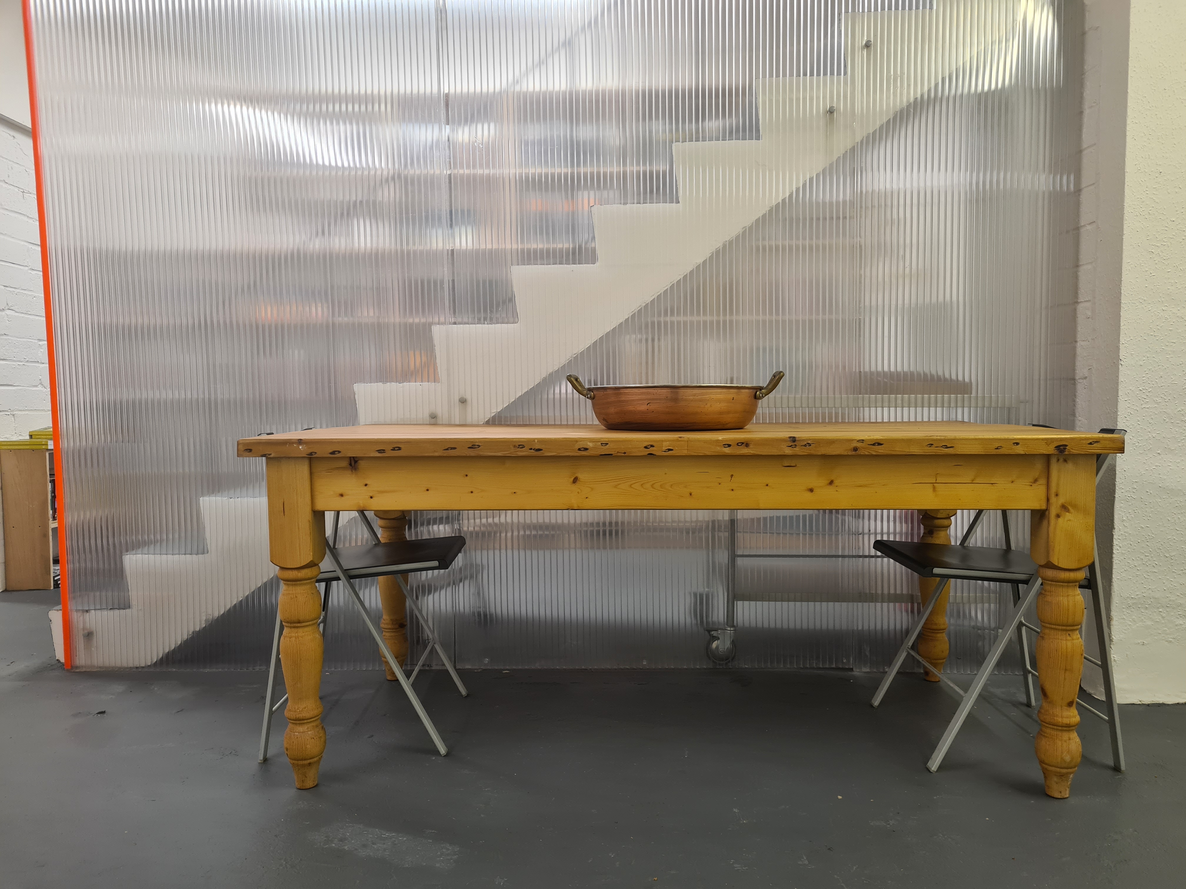 Minimalist meeting space with rustic wooden table and folding chairs in B. T. Batsford Gallery.