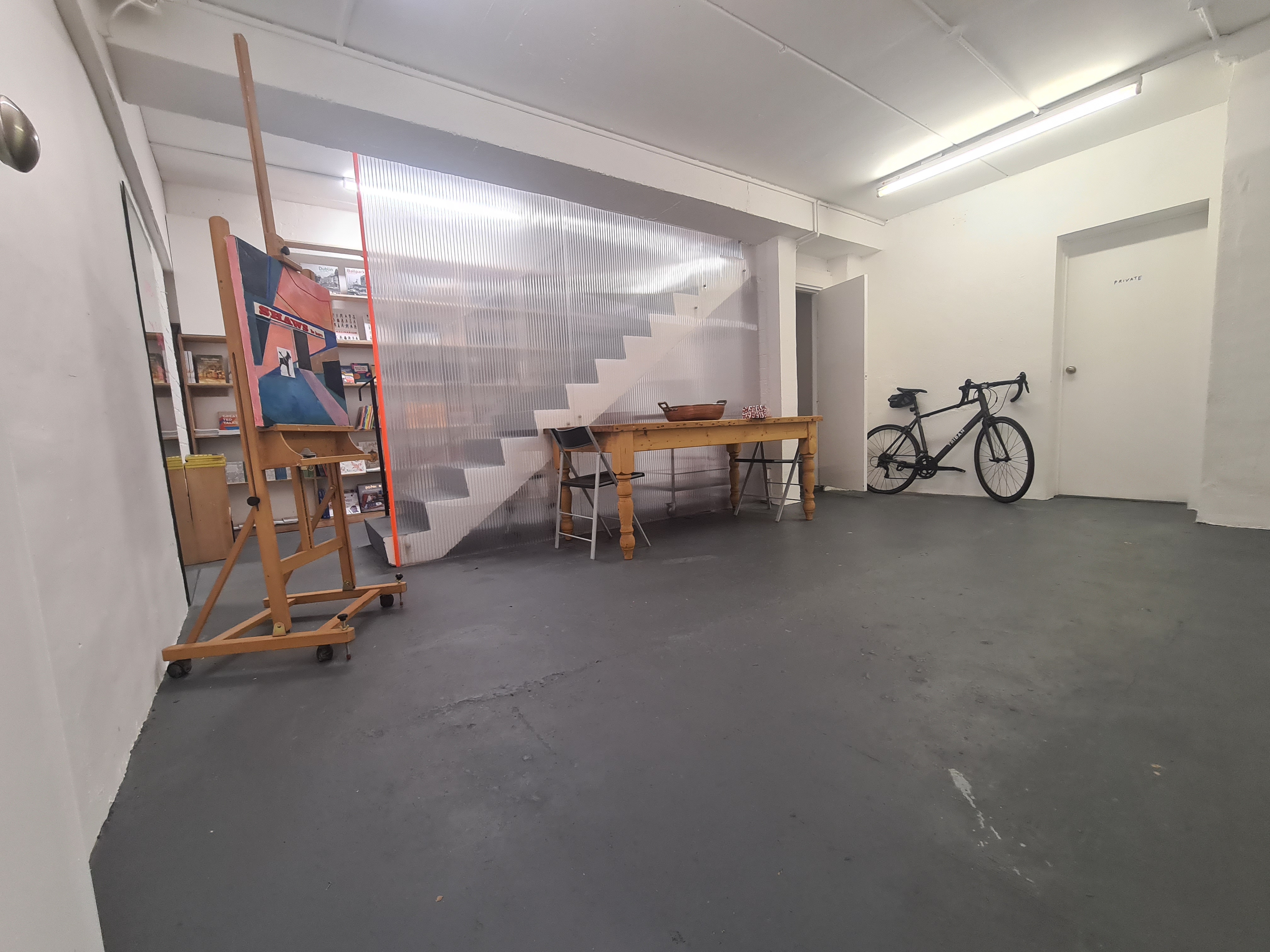 Minimalist workshop room with natural light, perfect for meetings and creative events.