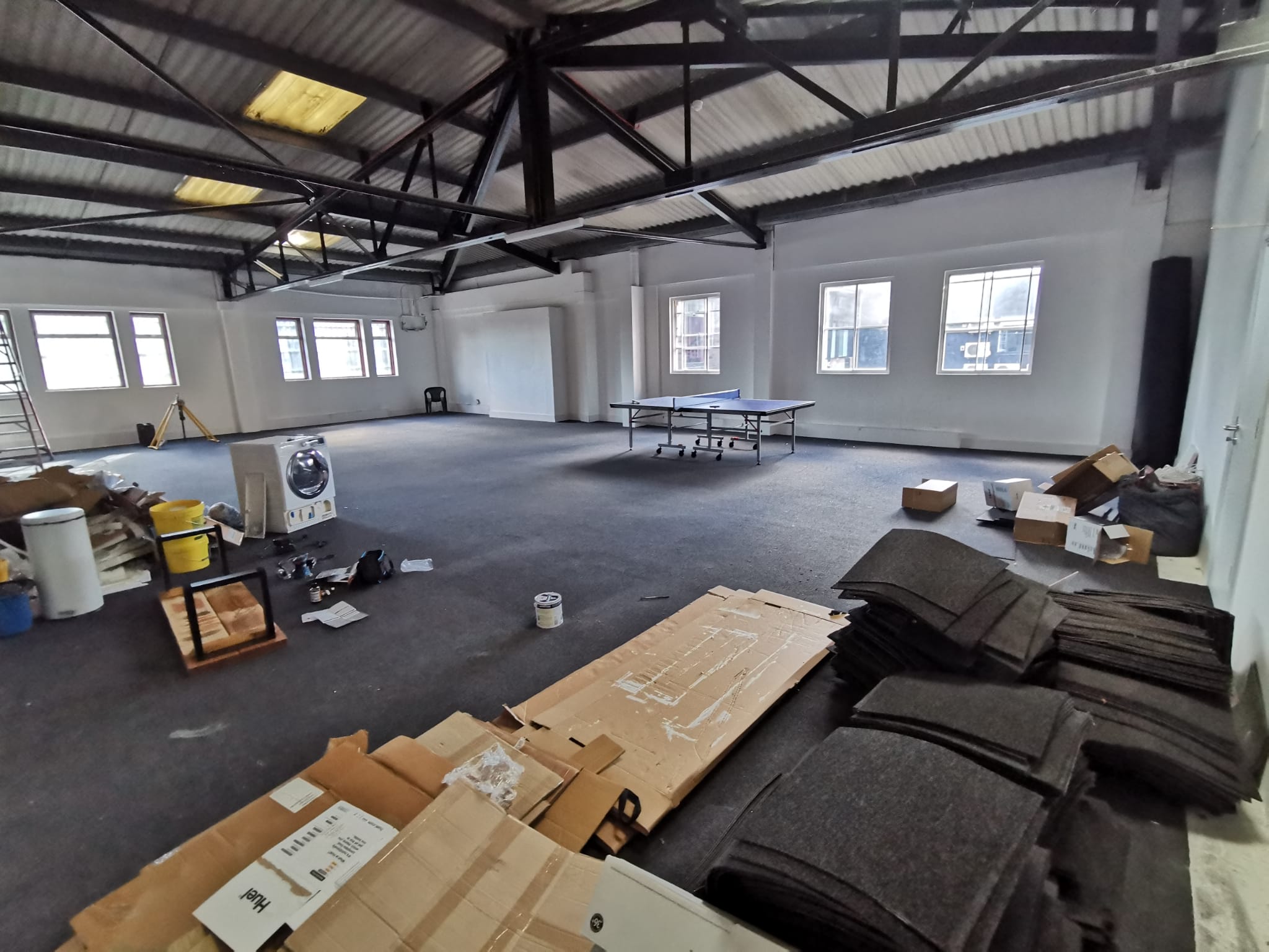 Spacious unfinished event space with high ceilings, ideal for meetings and workshops.