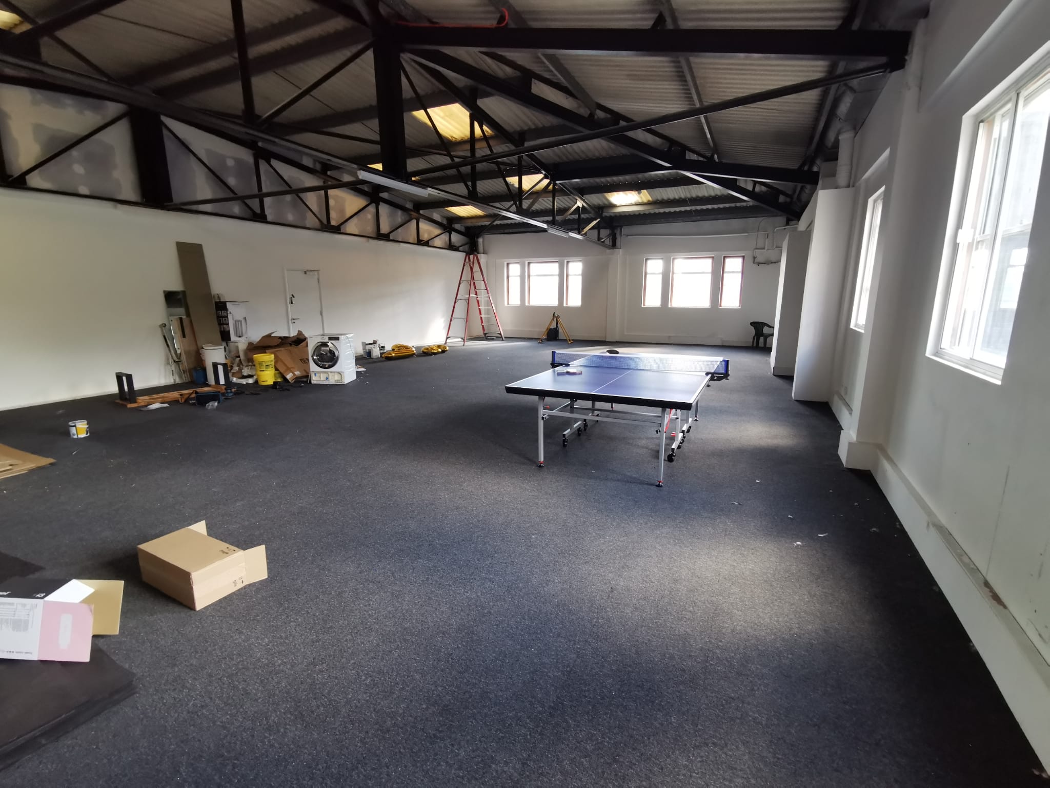 Spacious unfinished event space with high ceilings for workshops and gatherings.