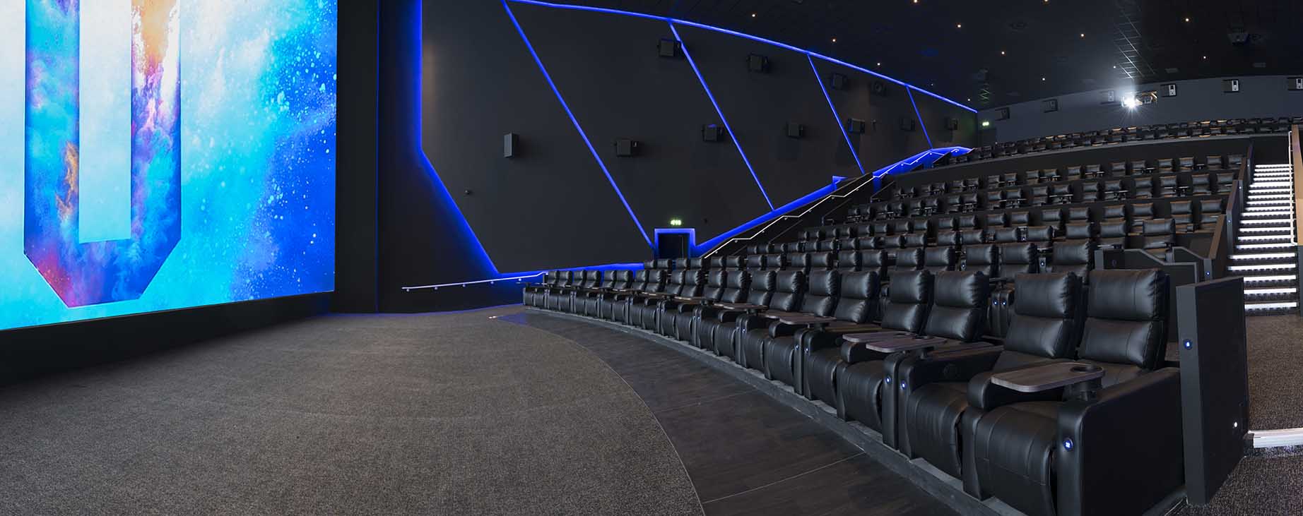 Modern auditorium with tiered seating and high-tech screen for conferences and film screenings.