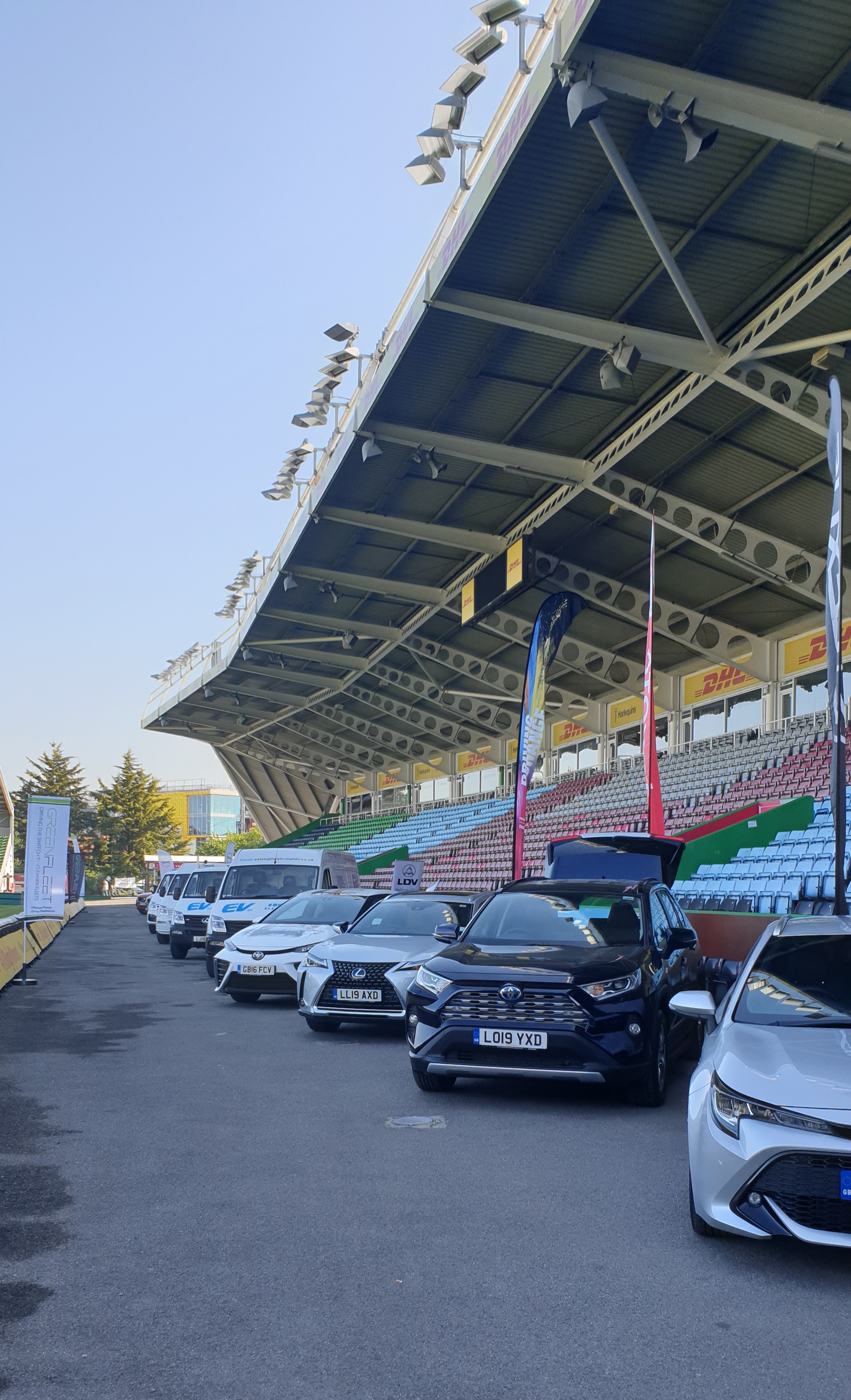 Outdoor automotive event at Twickenham Stoop Stadium with vehicles under grandstand.