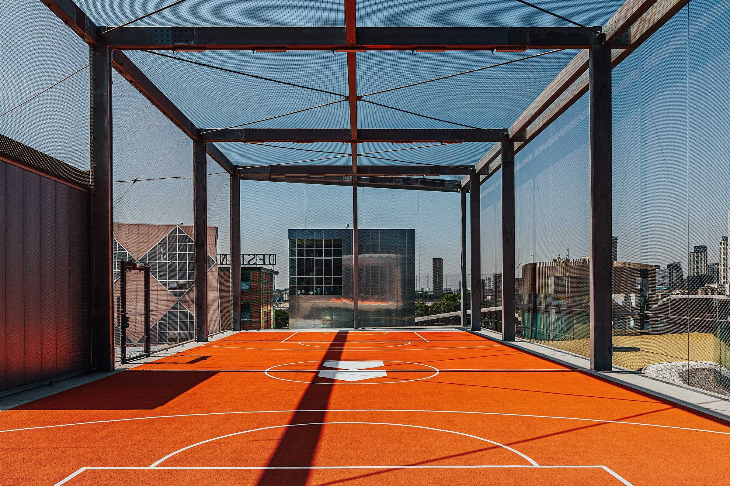 Rooftop event space in Design District London with vibrant orange basketball court.