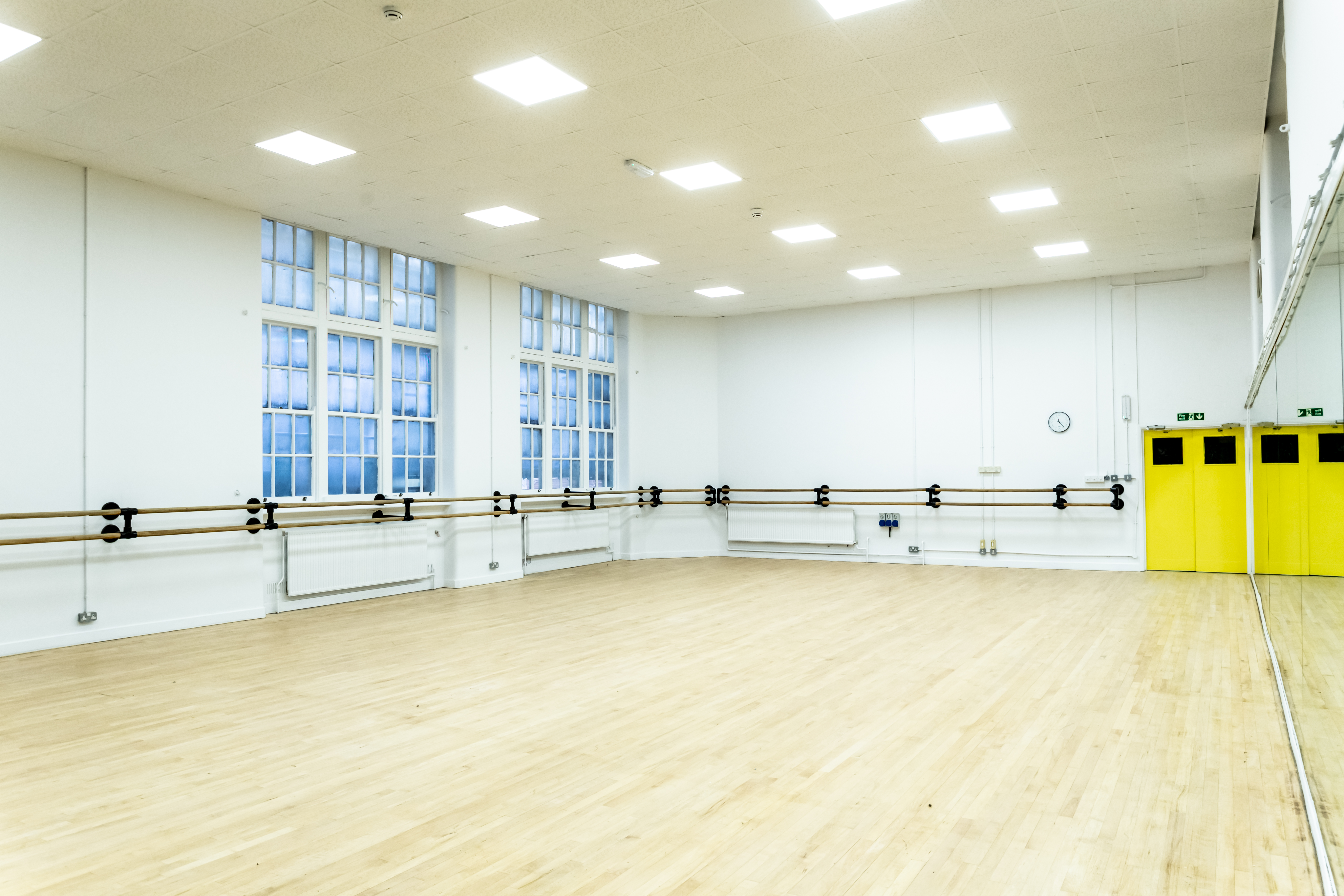 Spacious dance studio with wooden floors and large windows at City Academy, ideal for workshops.