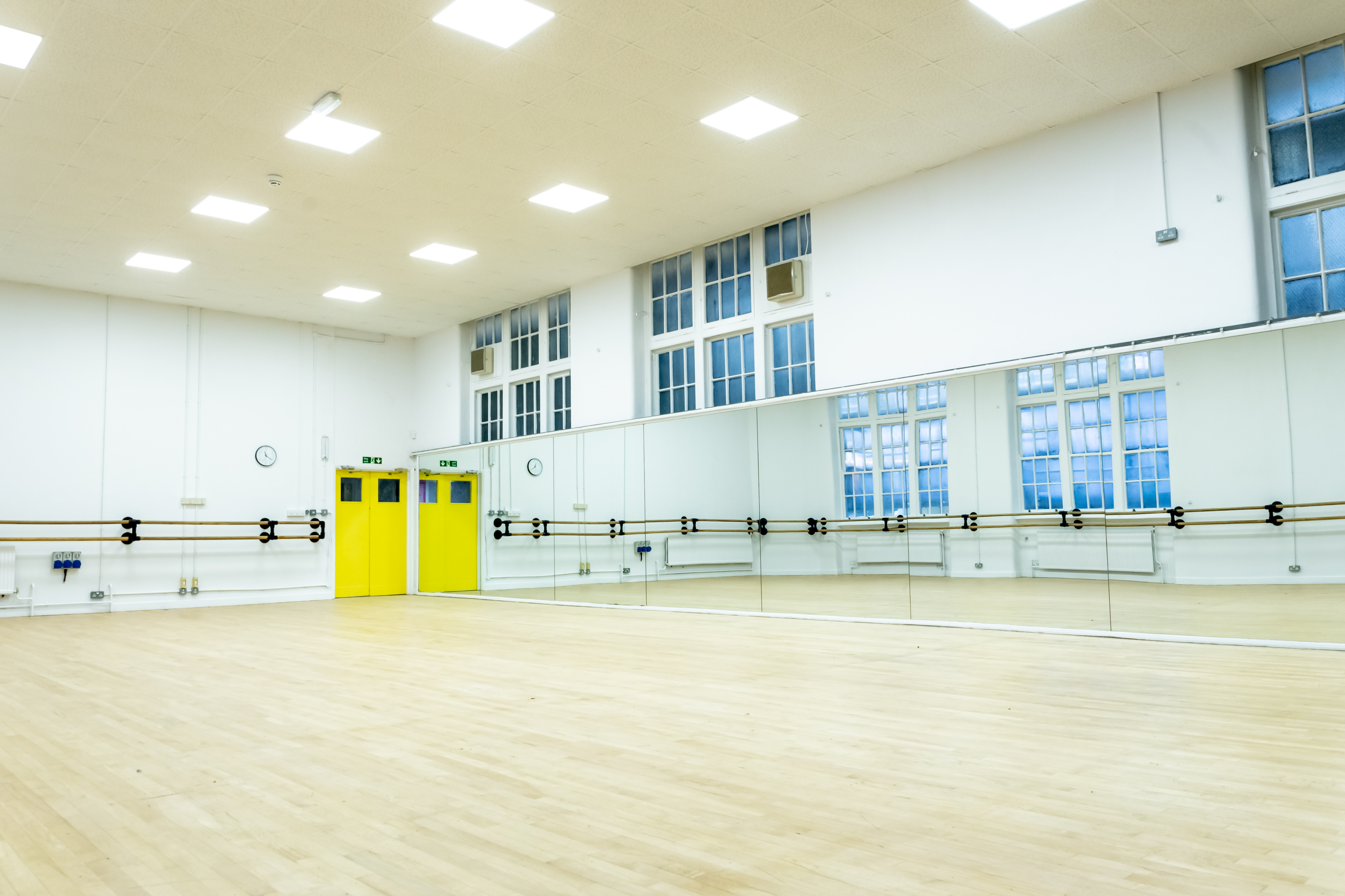 Spacious dance studio with mirrors and wooden floor, ideal for workshops and fitness classes.