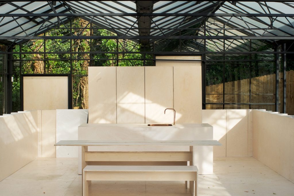 Modern glasshouse event space with sleek kitchen for intimate gatherings and culinary events.